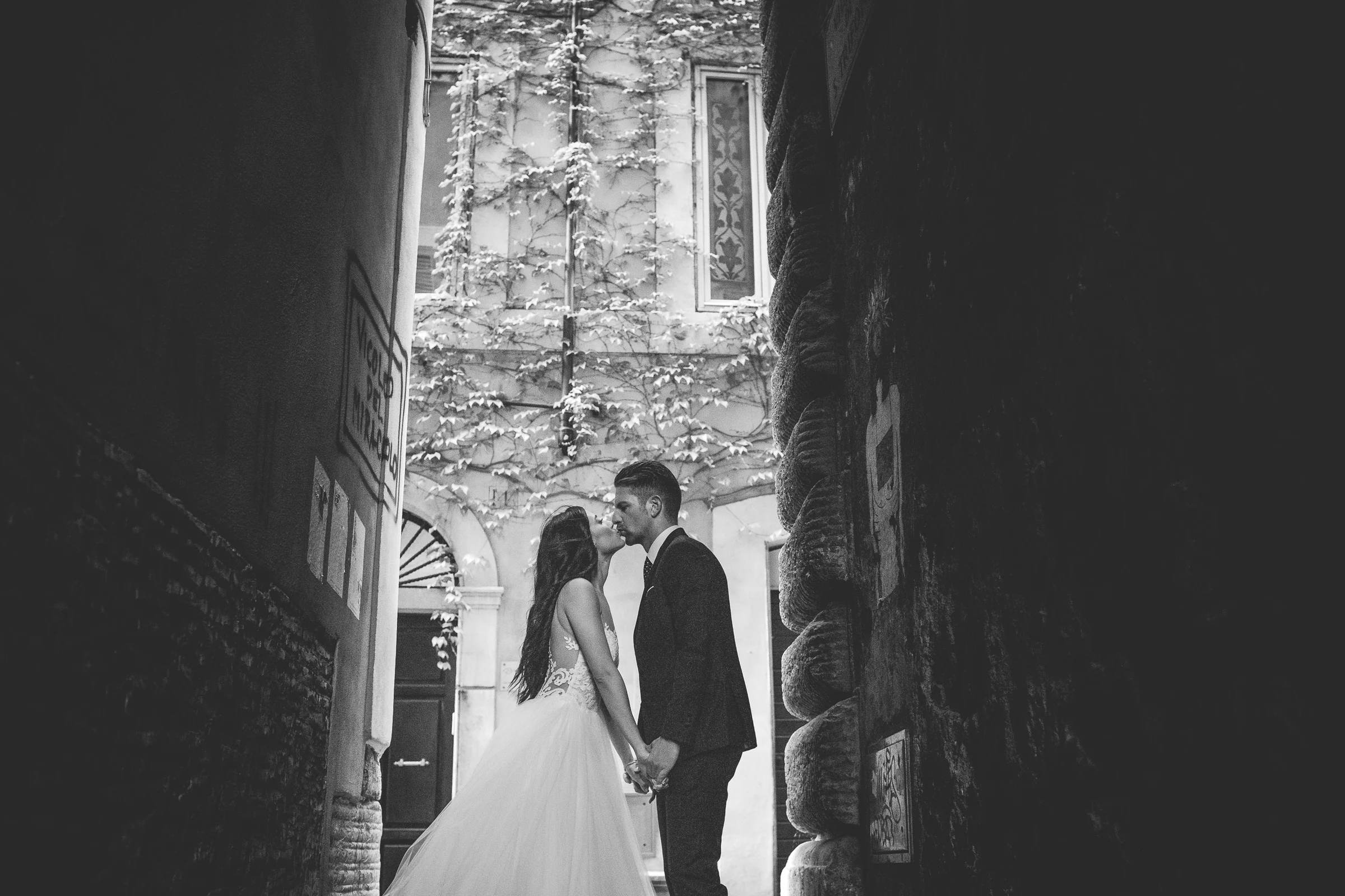 La pareja se besa en blanco y negro bajo un pasaje estrecho del centro de Roma durante una sesión postboda en Centro histórico de Roma.