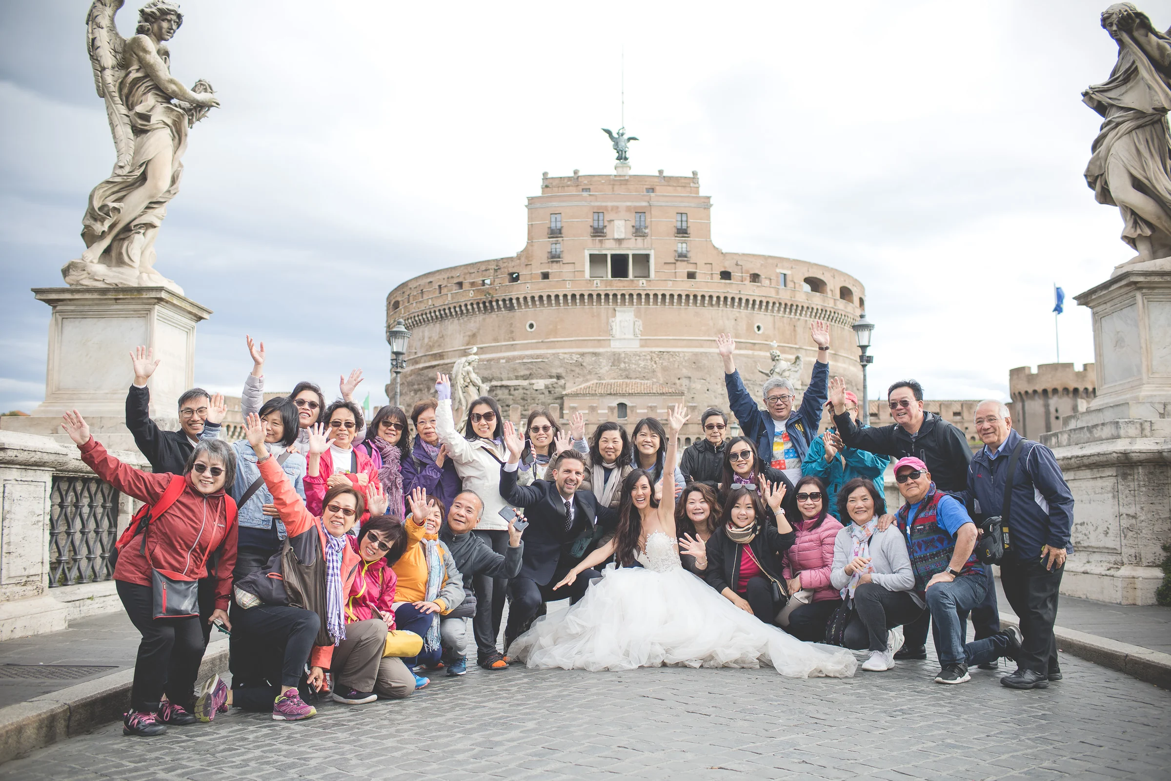 Los novios celebran rodeados de un grupo de turistas en el Ponte Sant’Angelo durante una sesión postboda en Ponte Sant’Angelo y río Tíber.