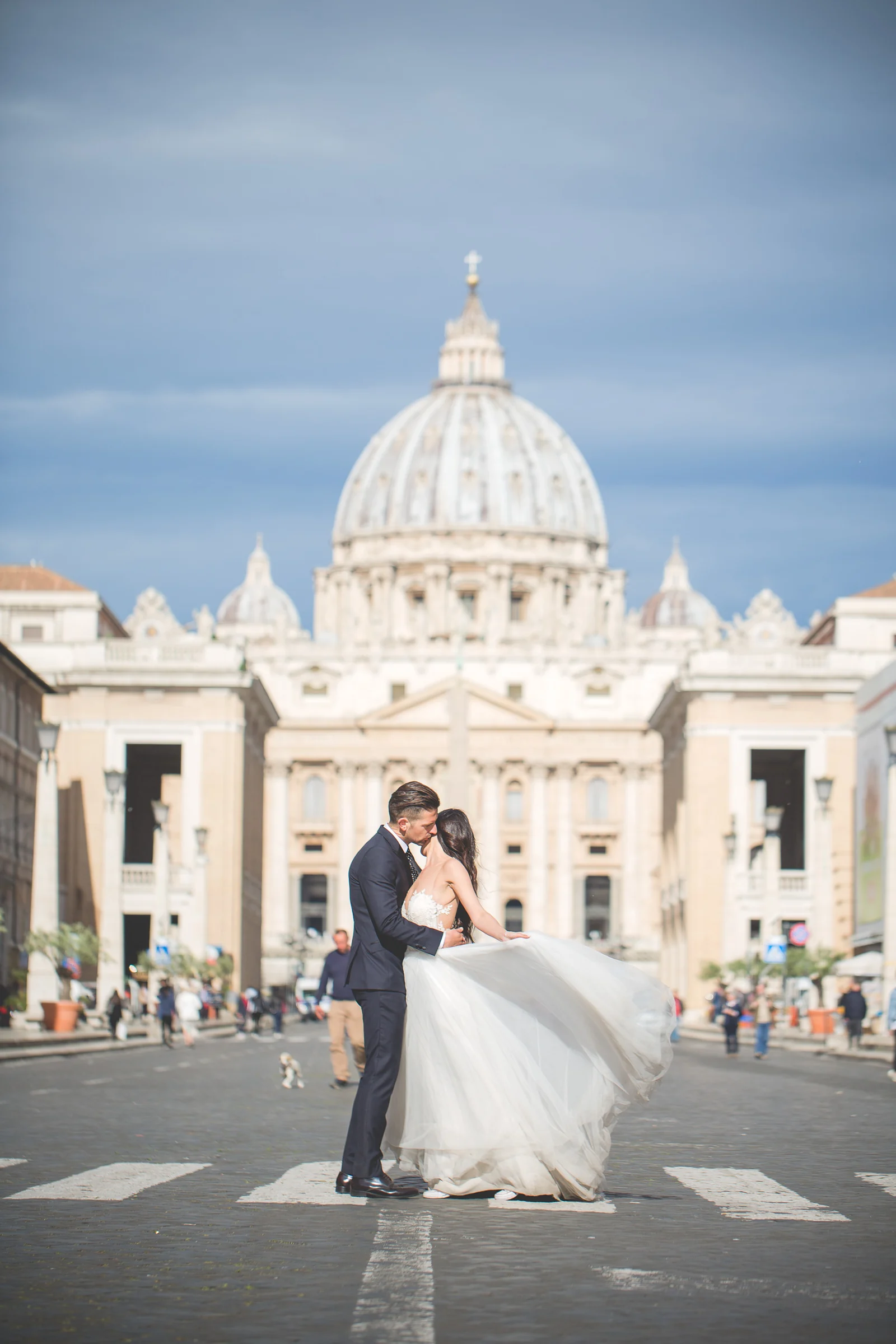 Los novios se besan en el centro de Via della Conciliazione con la Basílica de San Pedro al fondo durante una sesión postboda en Vaticano y Plaza de San Pedro.