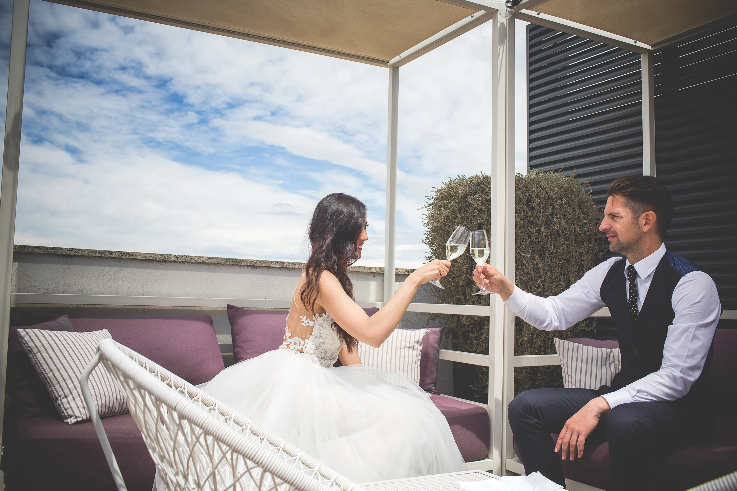 La pareja brinda con copas de espumoso en una terraza con vistas a Roma durante una sesión postboda en Terraza panorámica de Roma.