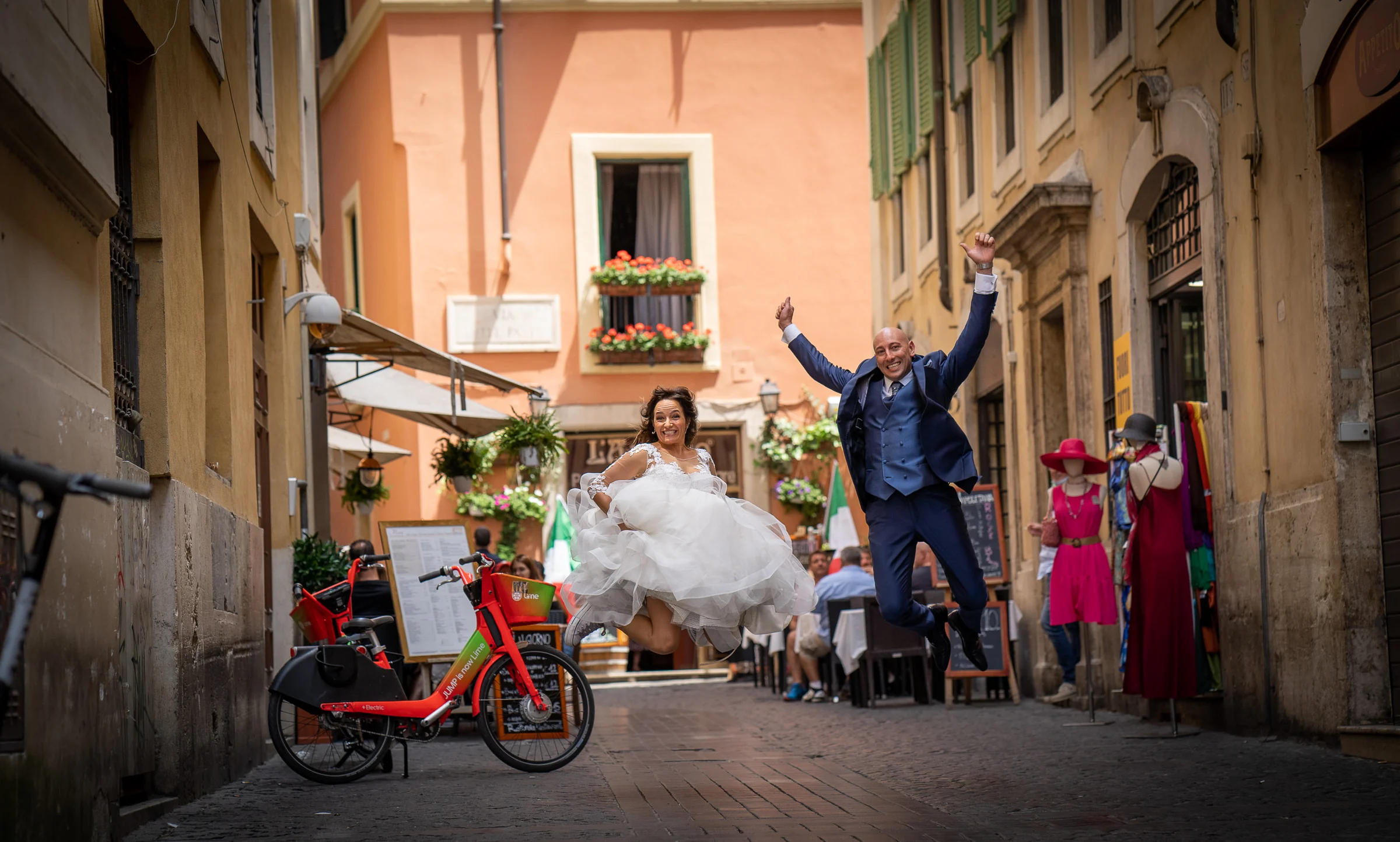 Marco y Esther saltan juntos en una calle adoquinada de Roma en una fotografía divertida y espontánea de su postboda.