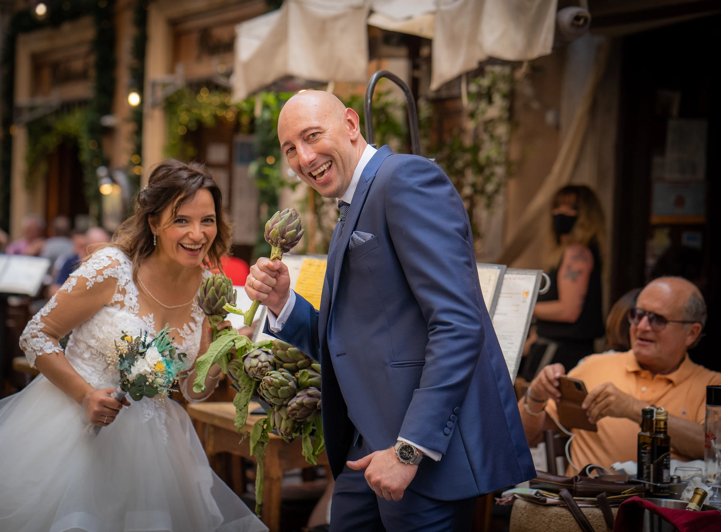 Marco y Esther bromean junto a un puesto de alcachofas en una calle del centro de Roma durante su reportaje postboda.
