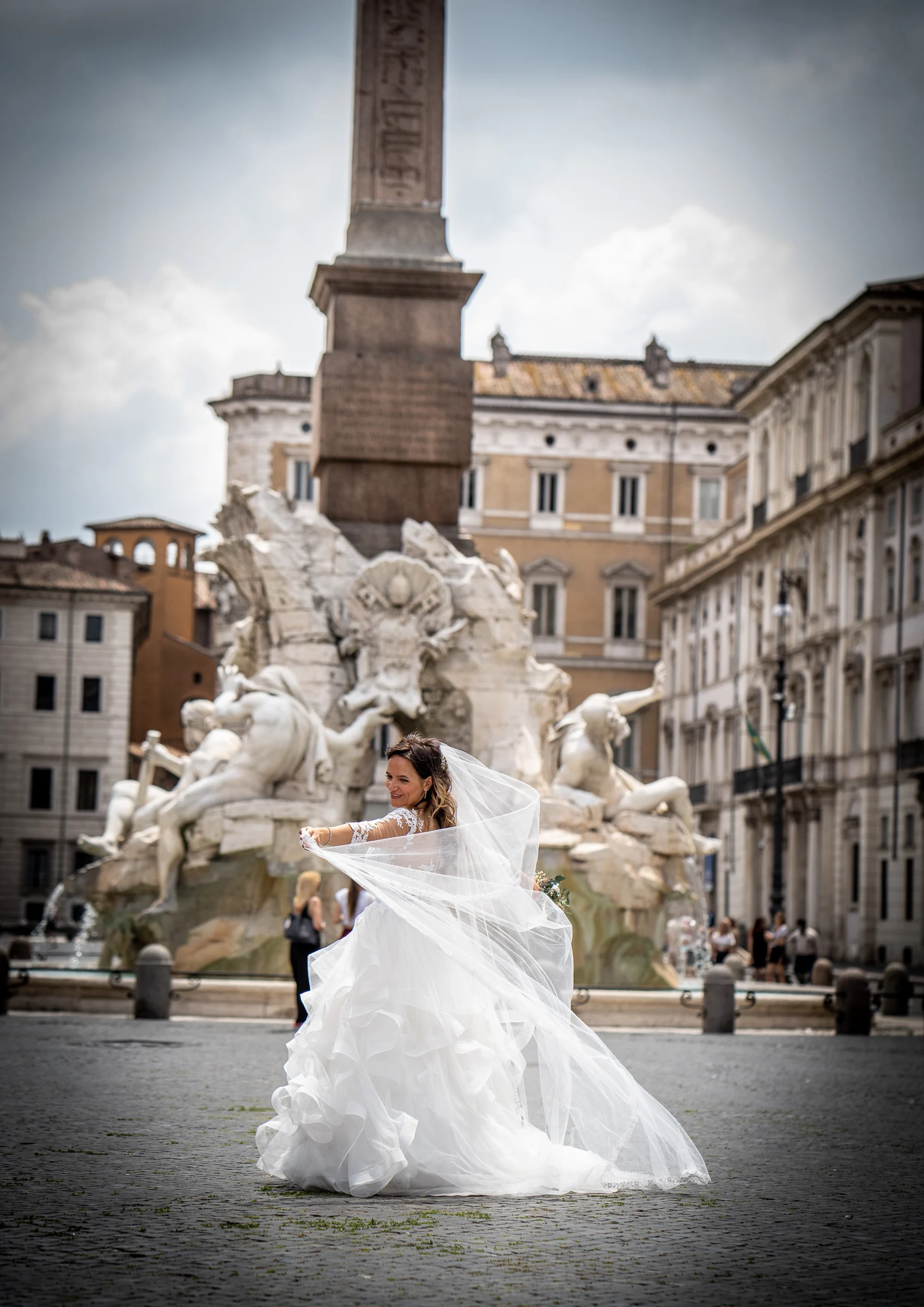 Esther posa con su vestido y velo frente a la Fontana dei Quattro Fiumi en Piazza Navona durante la postboda en Roma.