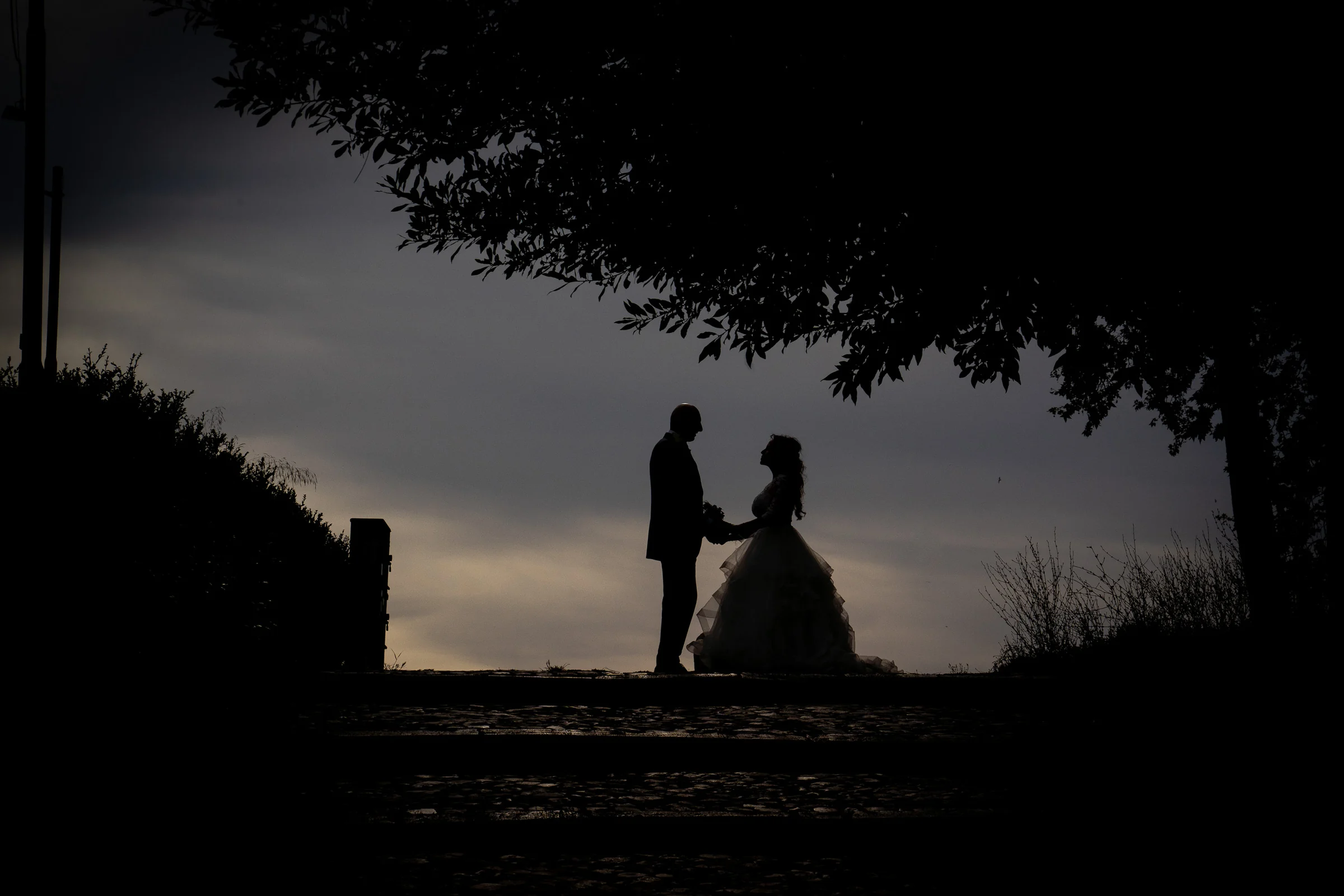 Silueta de Marco y Esther frente al cielo de Roma en un retrato oscuro y romántico de su sesión postboda.