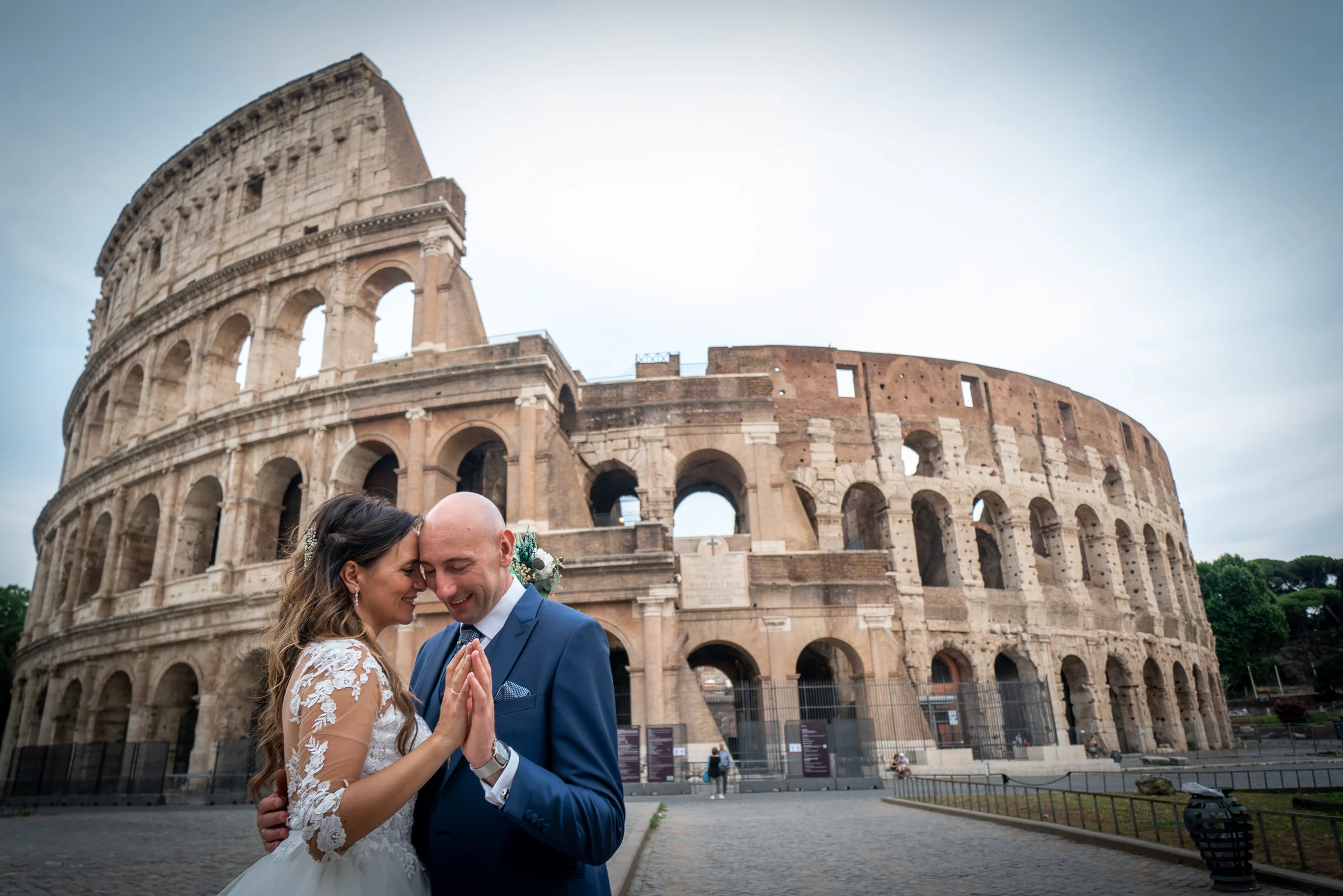 Marco y Esther se abrazan frente al Coliseo de Roma en un retrato íntimo con el monumento ocupando el fondo.