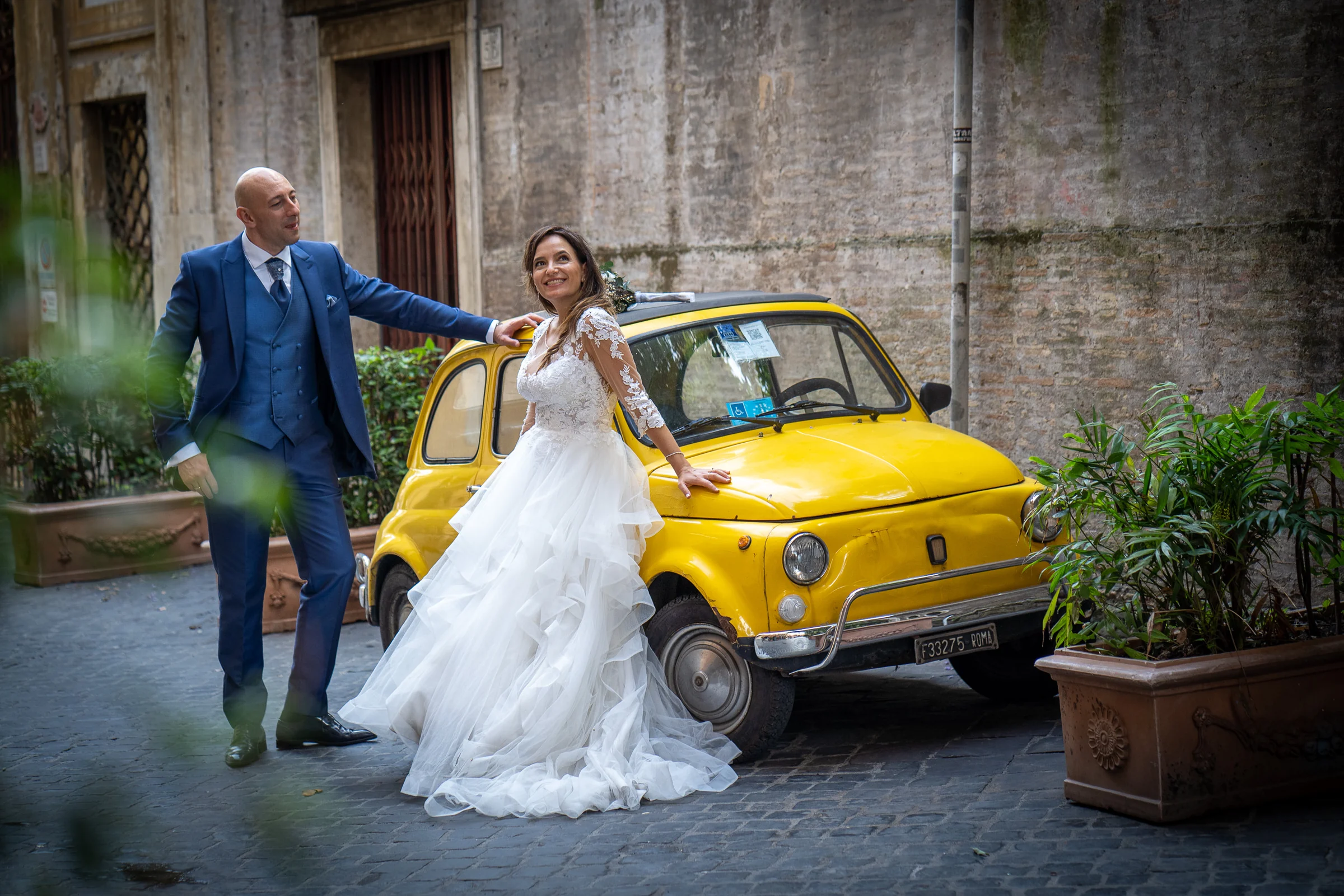 Marco y Esther posan junto a un Fiat 500 amarillo en una calle con encanto del centro de Roma.
