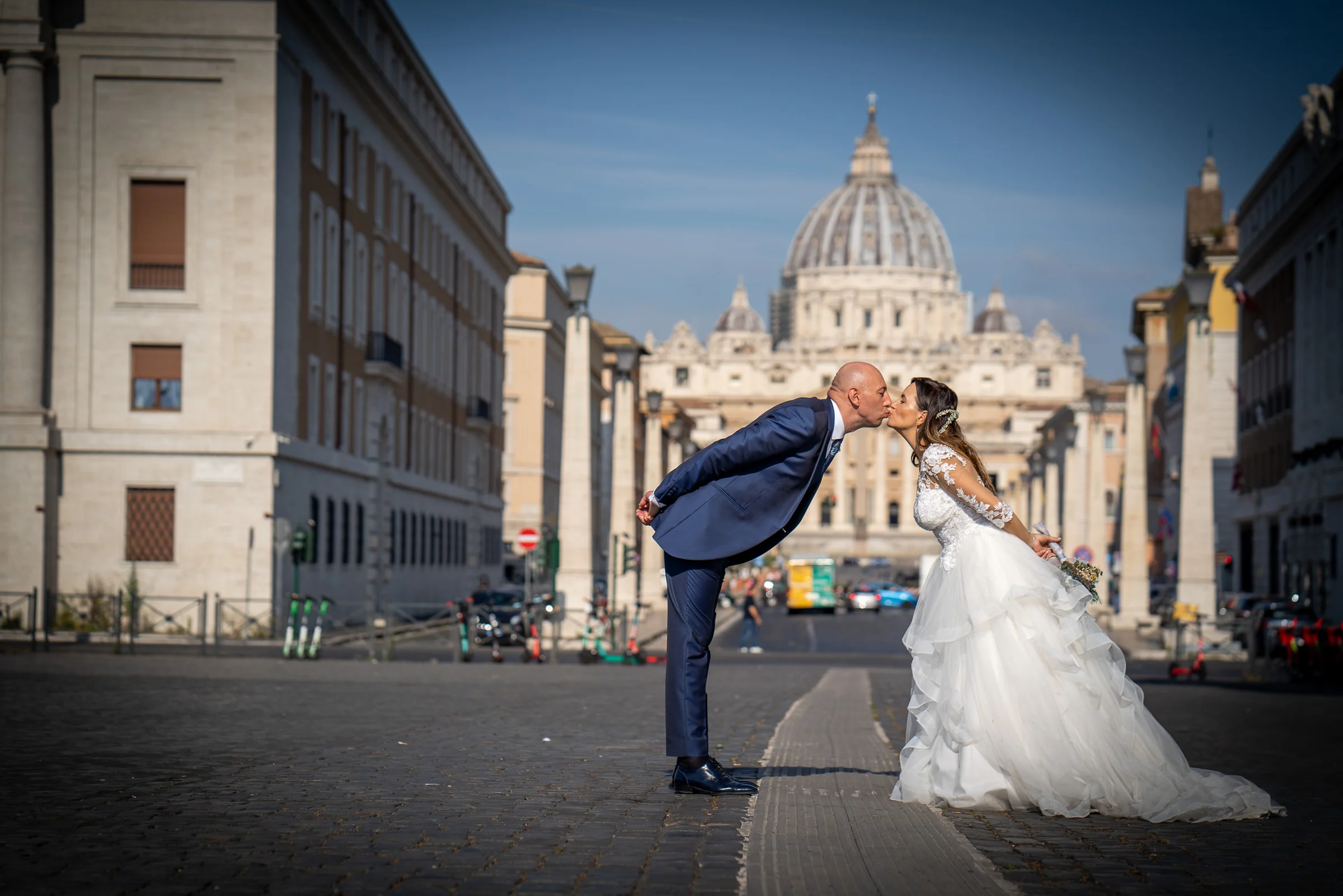 Marco y Esther se besan frente a la cúpula de San Pedro en una composición simétrica de su postboda en Roma.