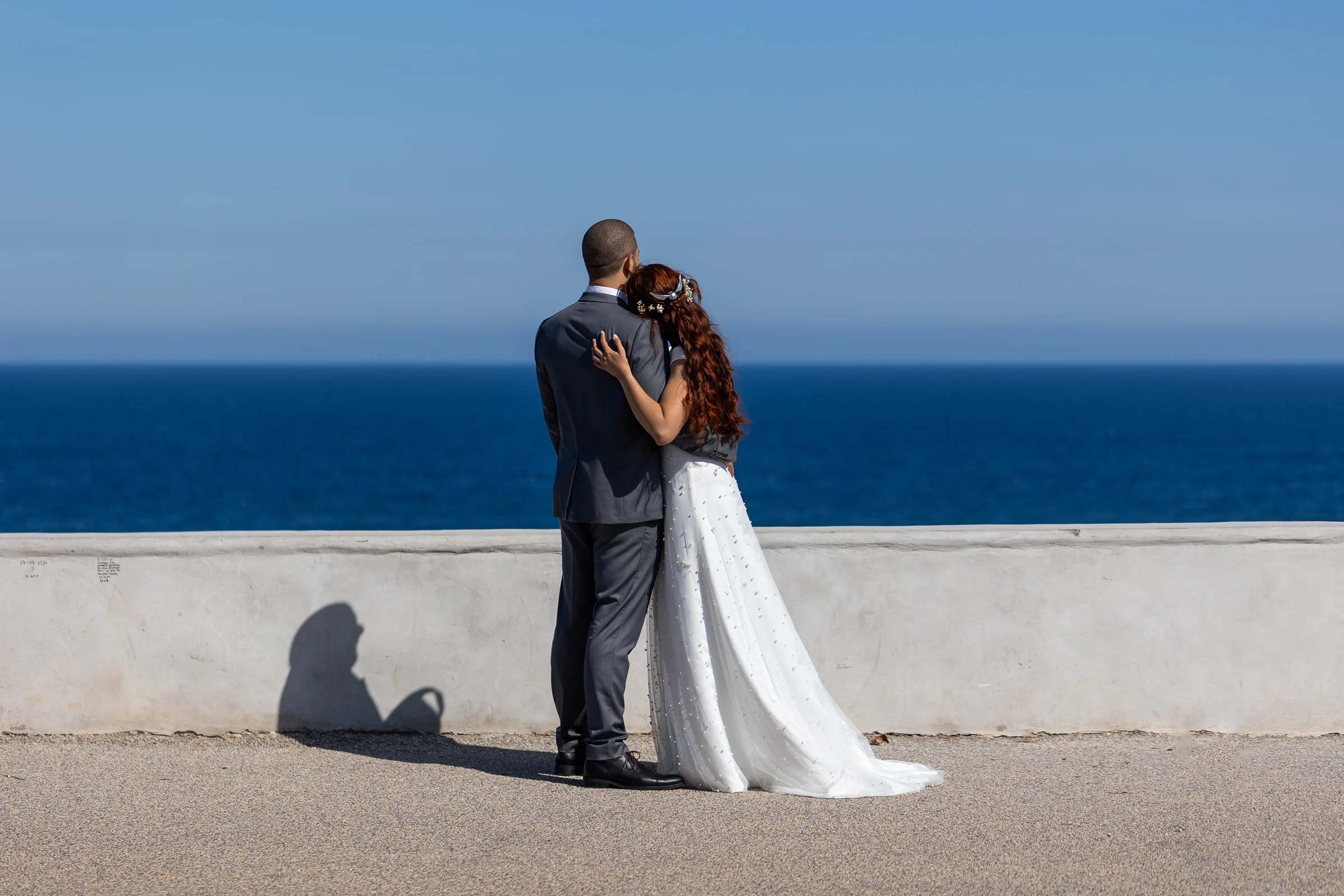 Noemí y Fran se abrazan de espaldas frente al mar en un mirador de Cartagena durante su postboda.