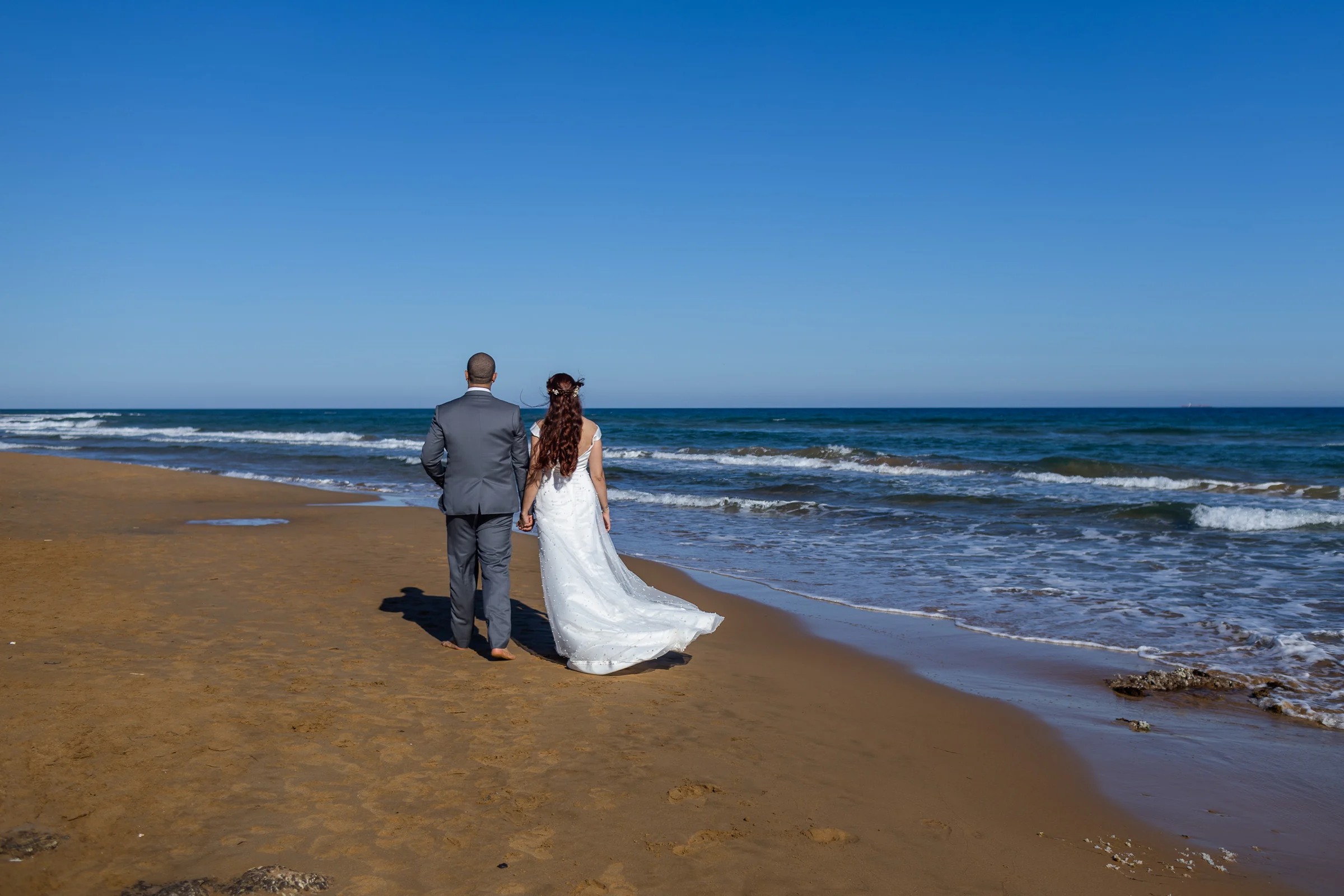 Noemí y Fran caminan descalzos por la orilla de la playa durante su postboda en Cartagena.