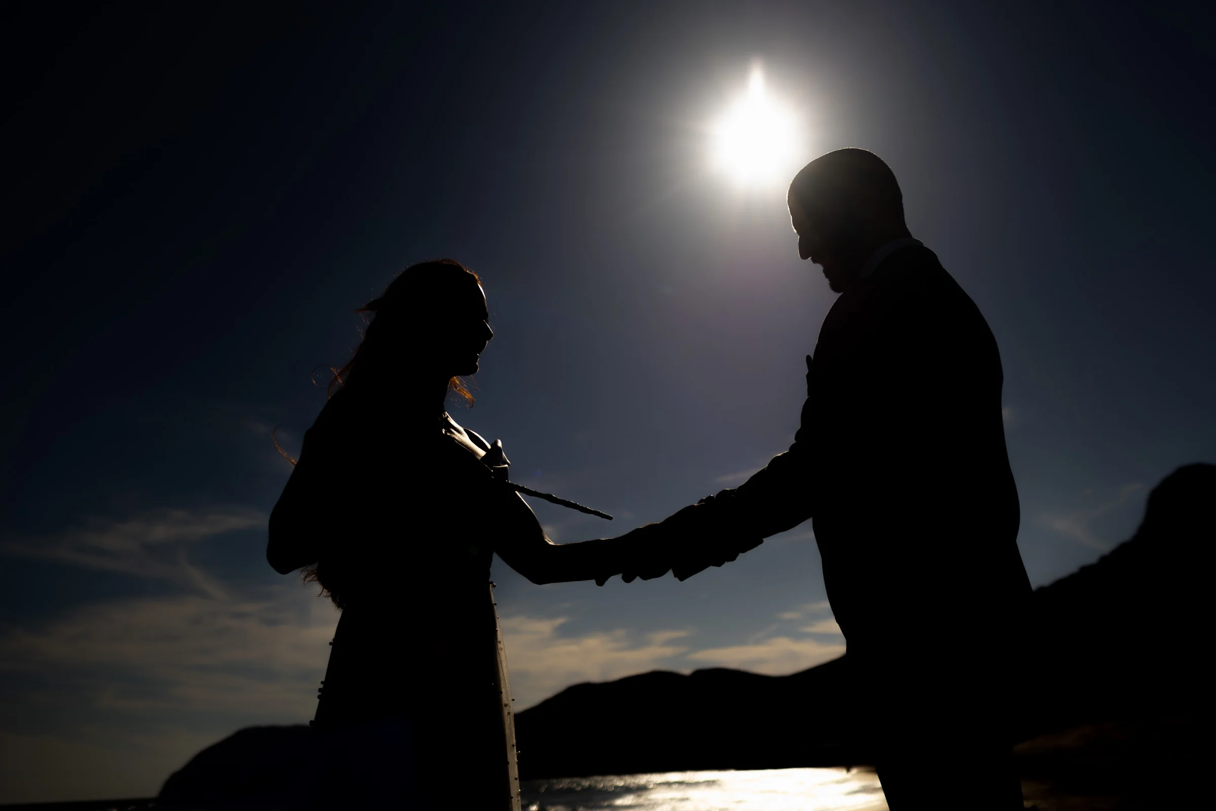 Silueta de Noemí y Fran frente al sol y al mar mientras comparten un momento mágico durante su postboda en Cartagena.