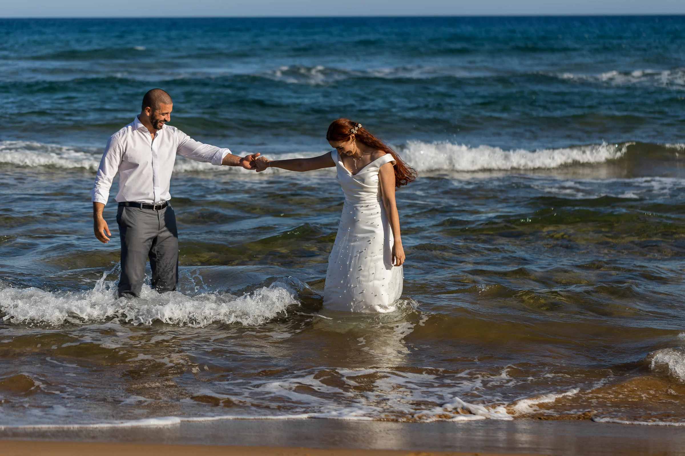 Noemí y Fran caminan de la mano dentro del agua durante su postboda en Cartagena.