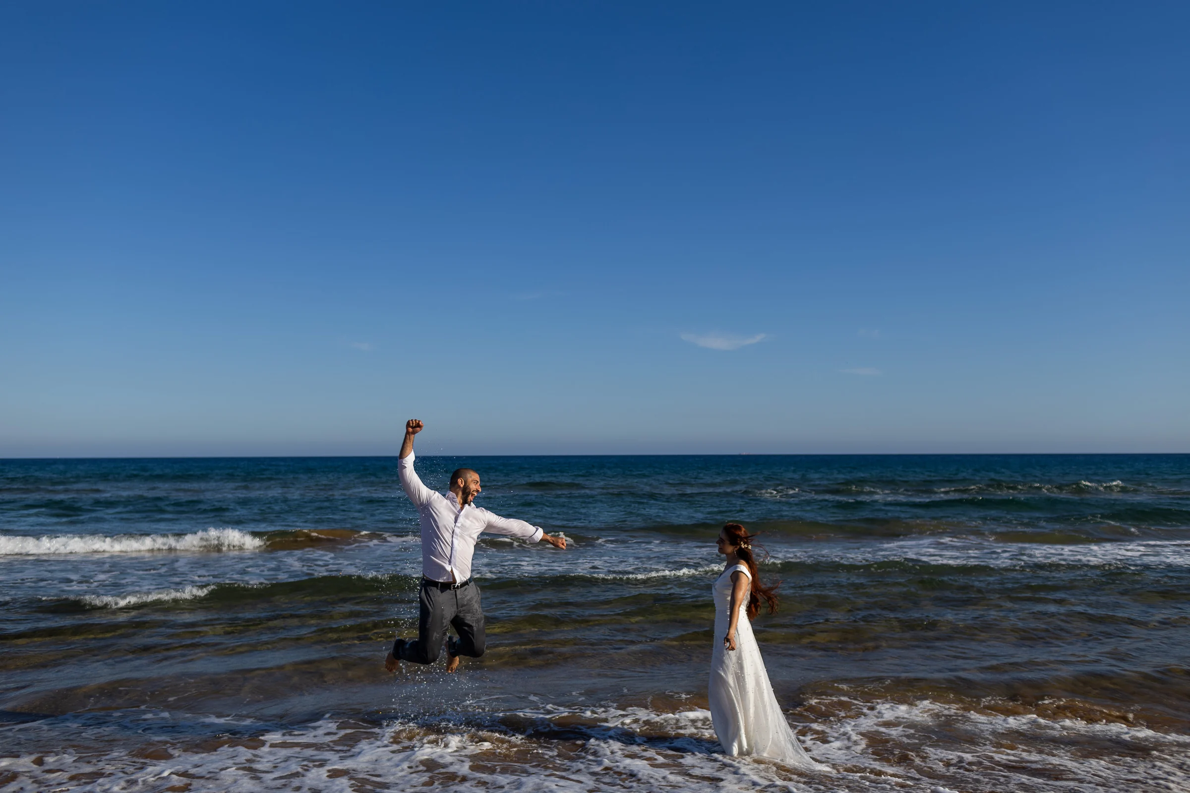 Fran salta dentro del agua con alegría mientras Noemí lo observa sonriente durante su postboda en Cartagena.