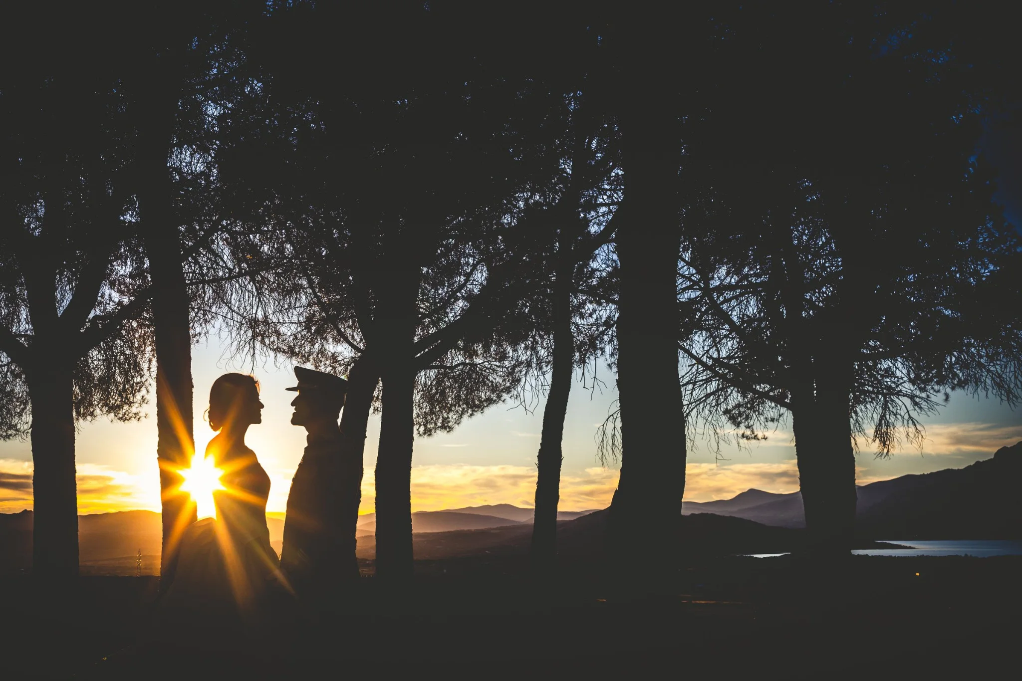 Silueta de los novios con el sol entre los árboles en una boda en Peñarrubia de Araceli
