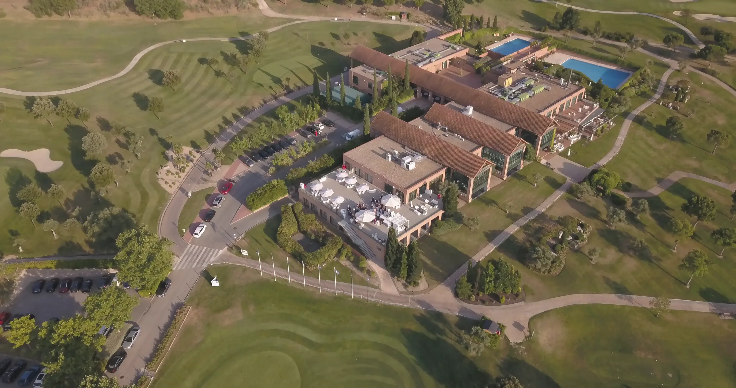 Vista aérea del conjunto de edificios y la piscina entre el campo de golf de Retamares Experience.