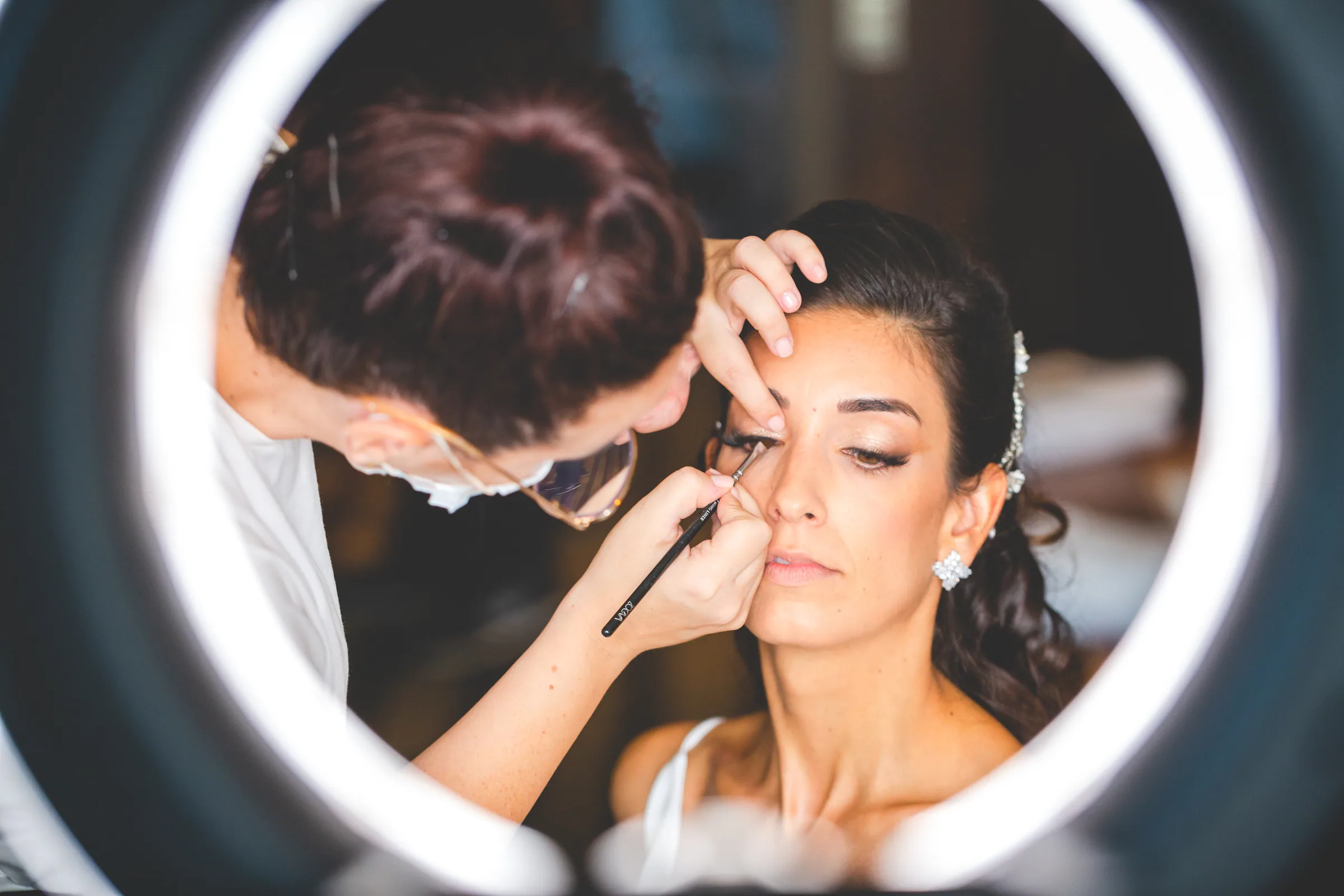 Maquillaje de la novia reflejado en un espejo con aro de luz en Retamares Experience.