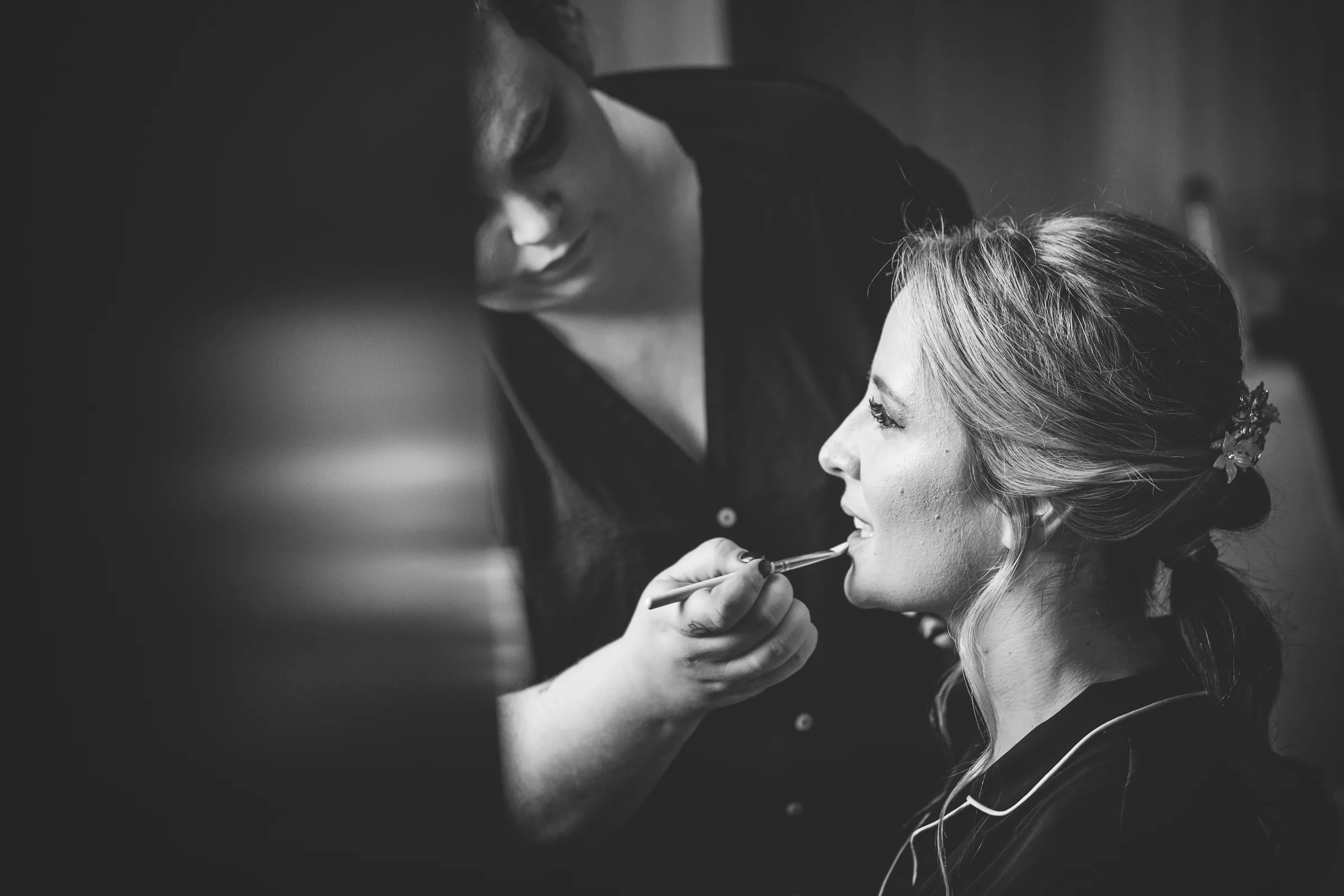 Retoque de labios de la novia en blanco y negro durante el maquillaje en Retamares Experience.