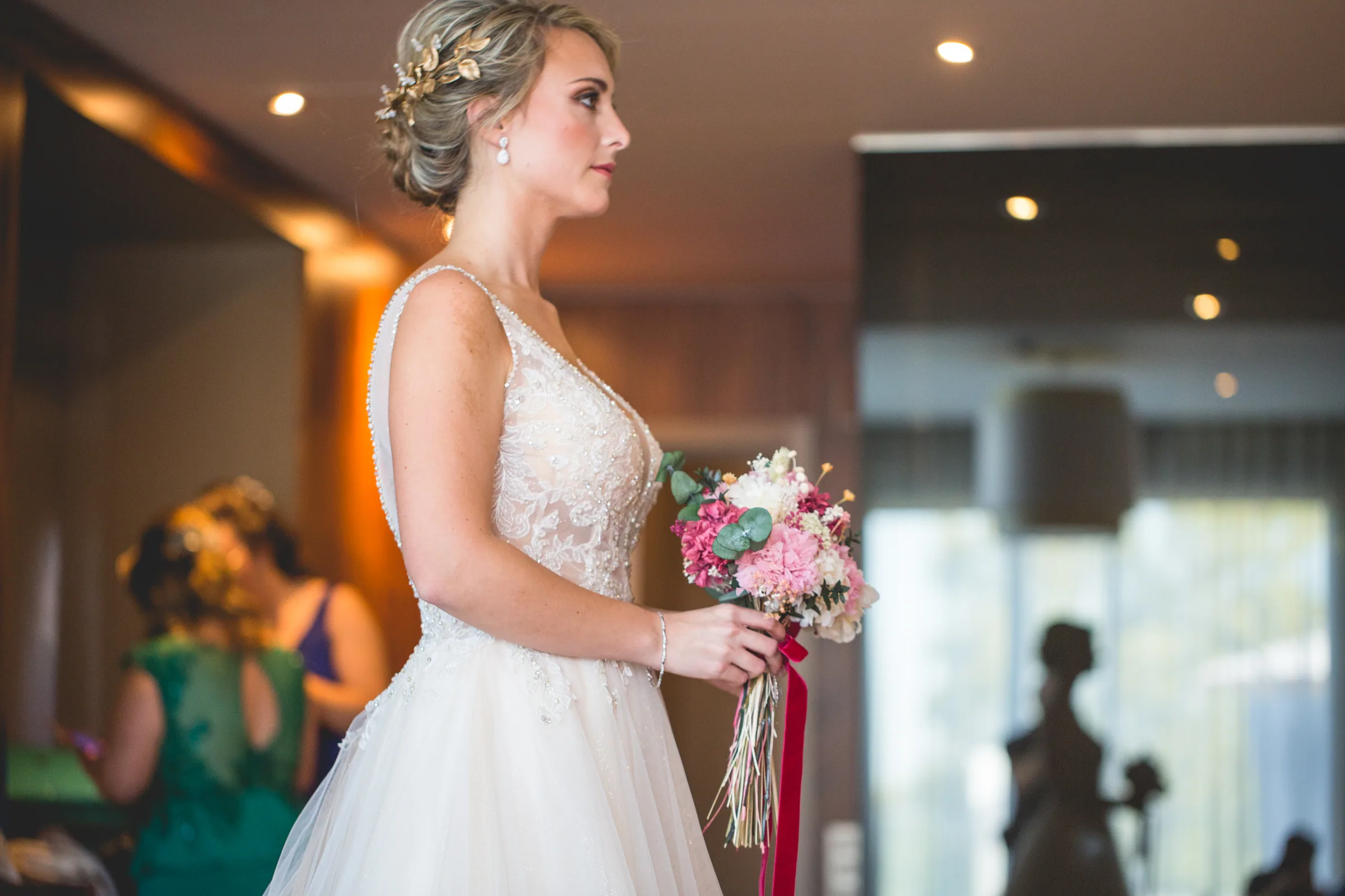 La novia de perfil con su ramo en la habitación del hotel antes de la ceremonia en Retamares Experience.