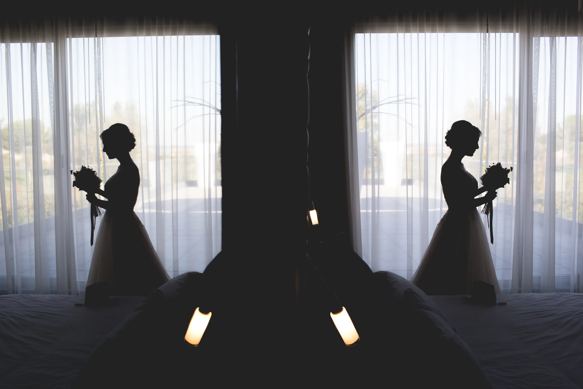 Silueta de la novia con su ramo frente al ventanal, repetida en el reflejo de un espejo en Retamares Experience.