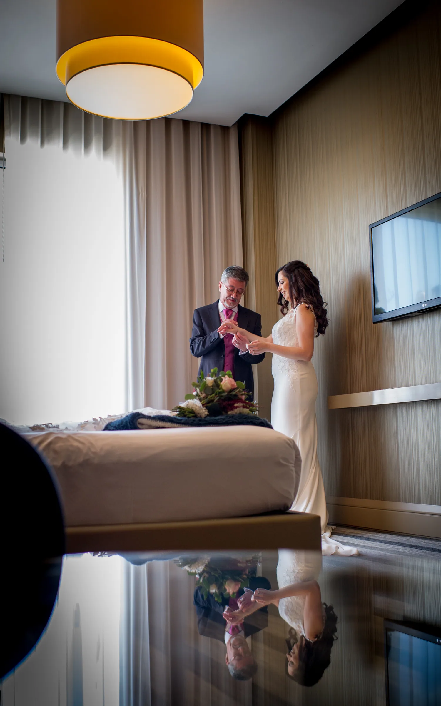 La novia de blanco reflejada en el suelo brillante de una habitación del hotel antes de la ceremonia en Retamares Experience.