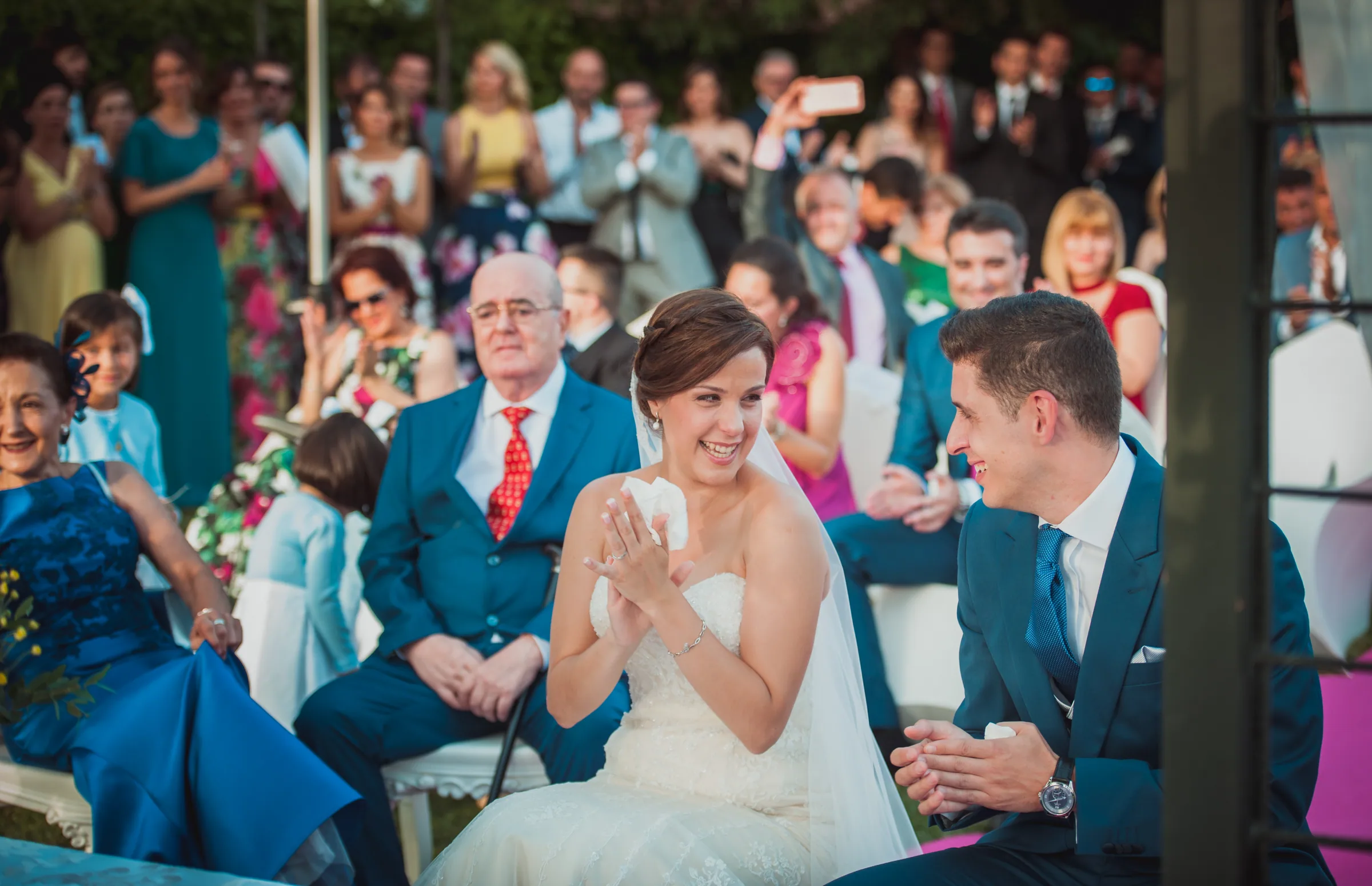 La novia aplaude sonriente junto al novio durante la ceremonia en Retamares Experience.