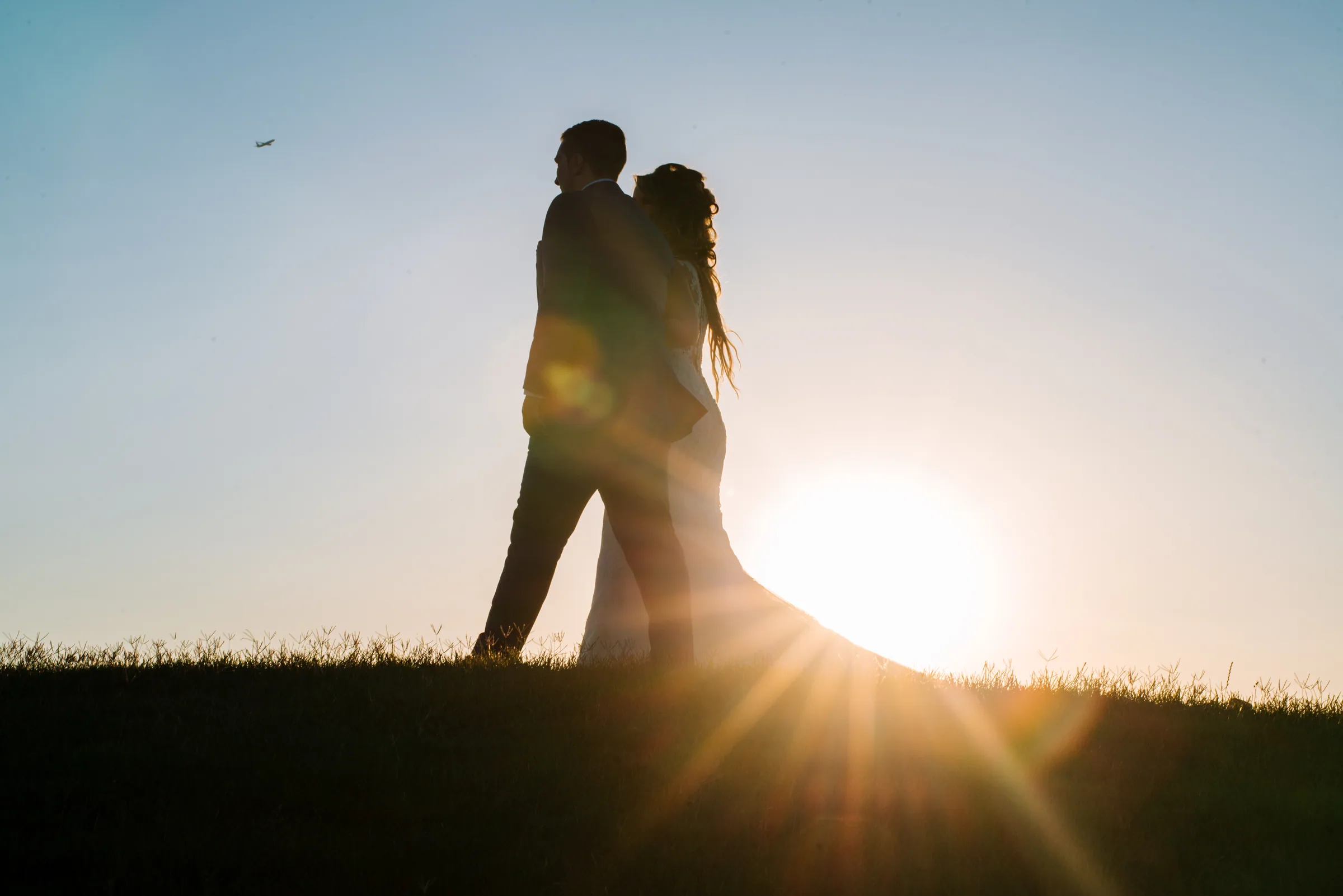 Silueta de los novios abrazados con el sol y sus rayos detrás en Retamares Experience.