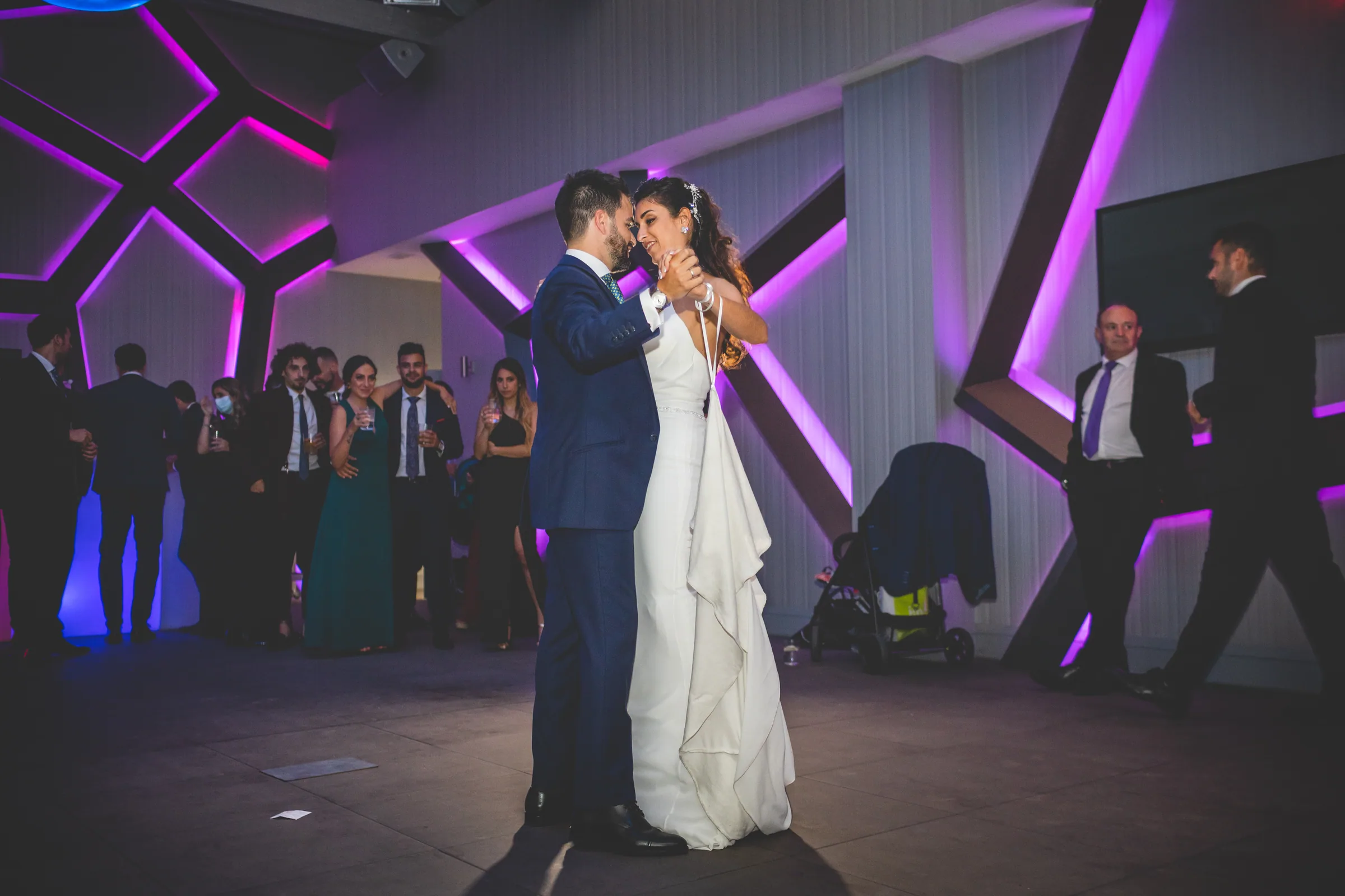 Primer baile de los novios bajo luces moradas con forma geométrica en Retamares Experience.