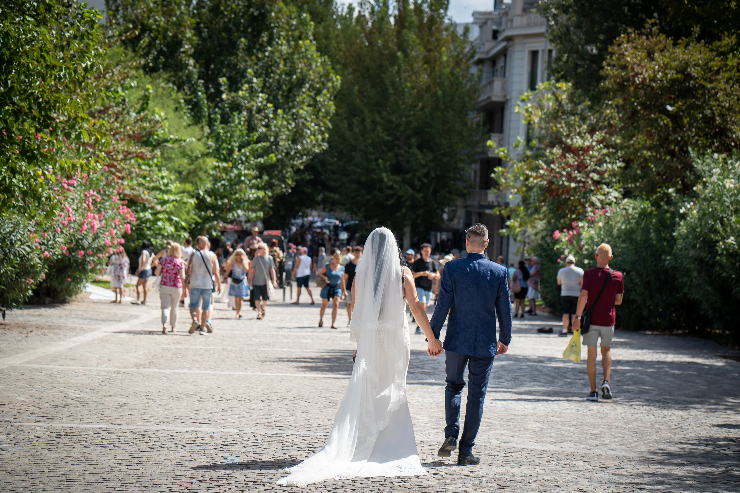 Sara y Edu caminan de la mano por una calle peatonal de Atenas durante su postboda en Grecia.