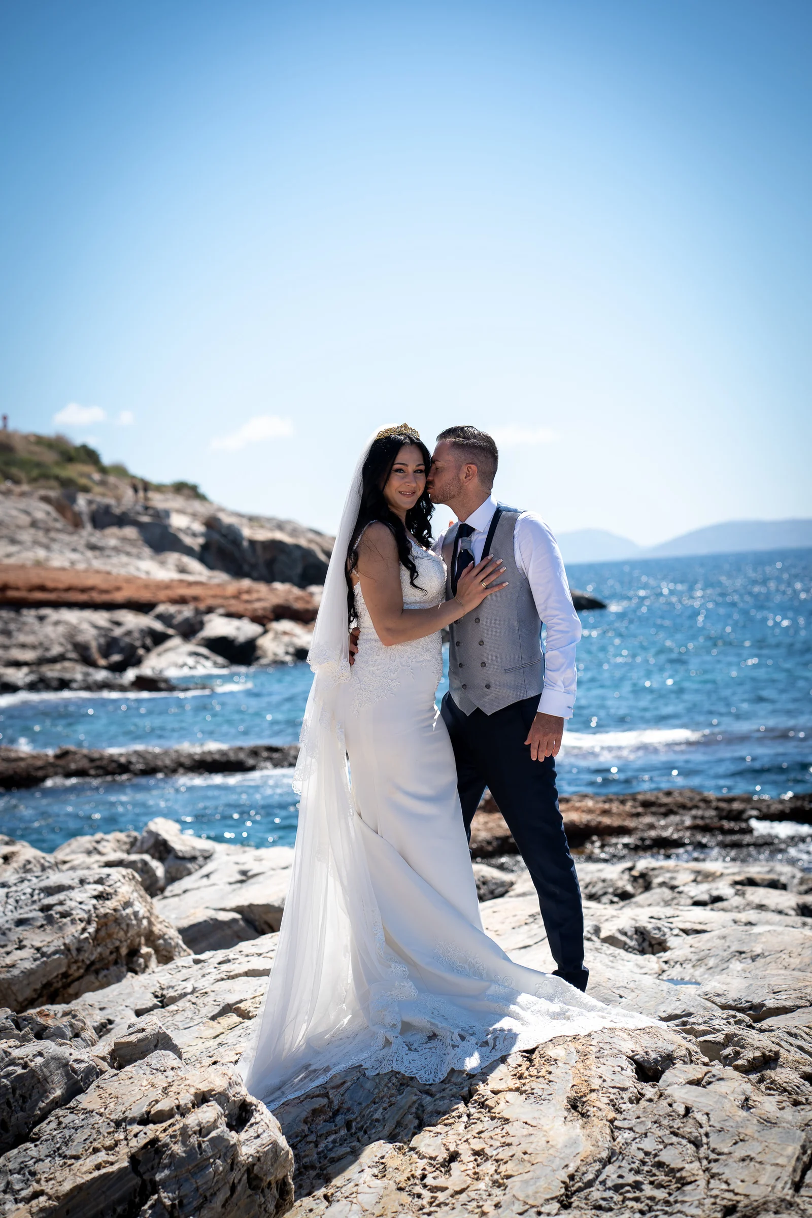 Edu besa a Sara junto al mar Egeo en una costa rocosa de Grecia durante su sesión de postboda.