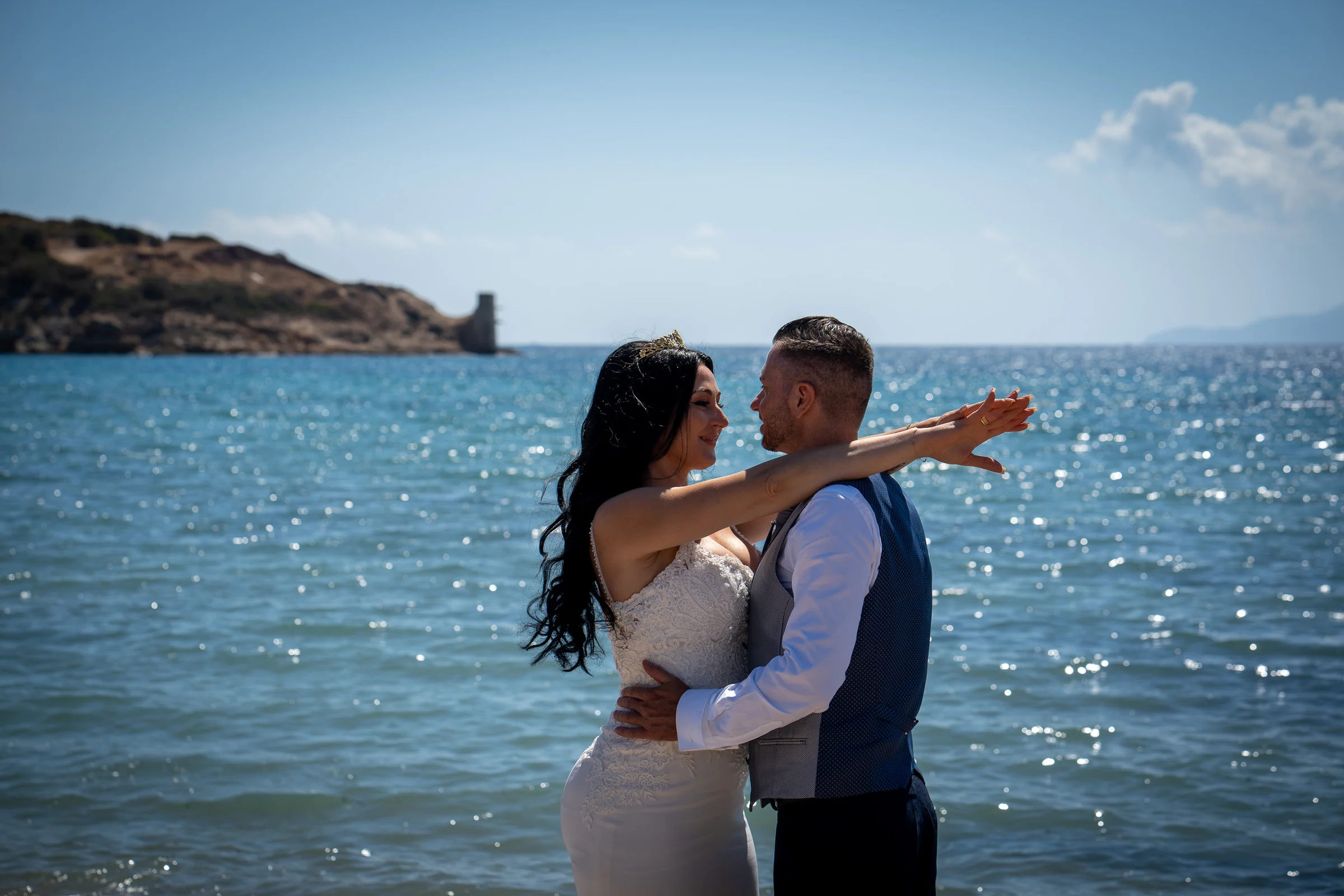 Sara abre los brazos junto a Edu frente al mar Egeo durante su postboda en la costa de Grecia.