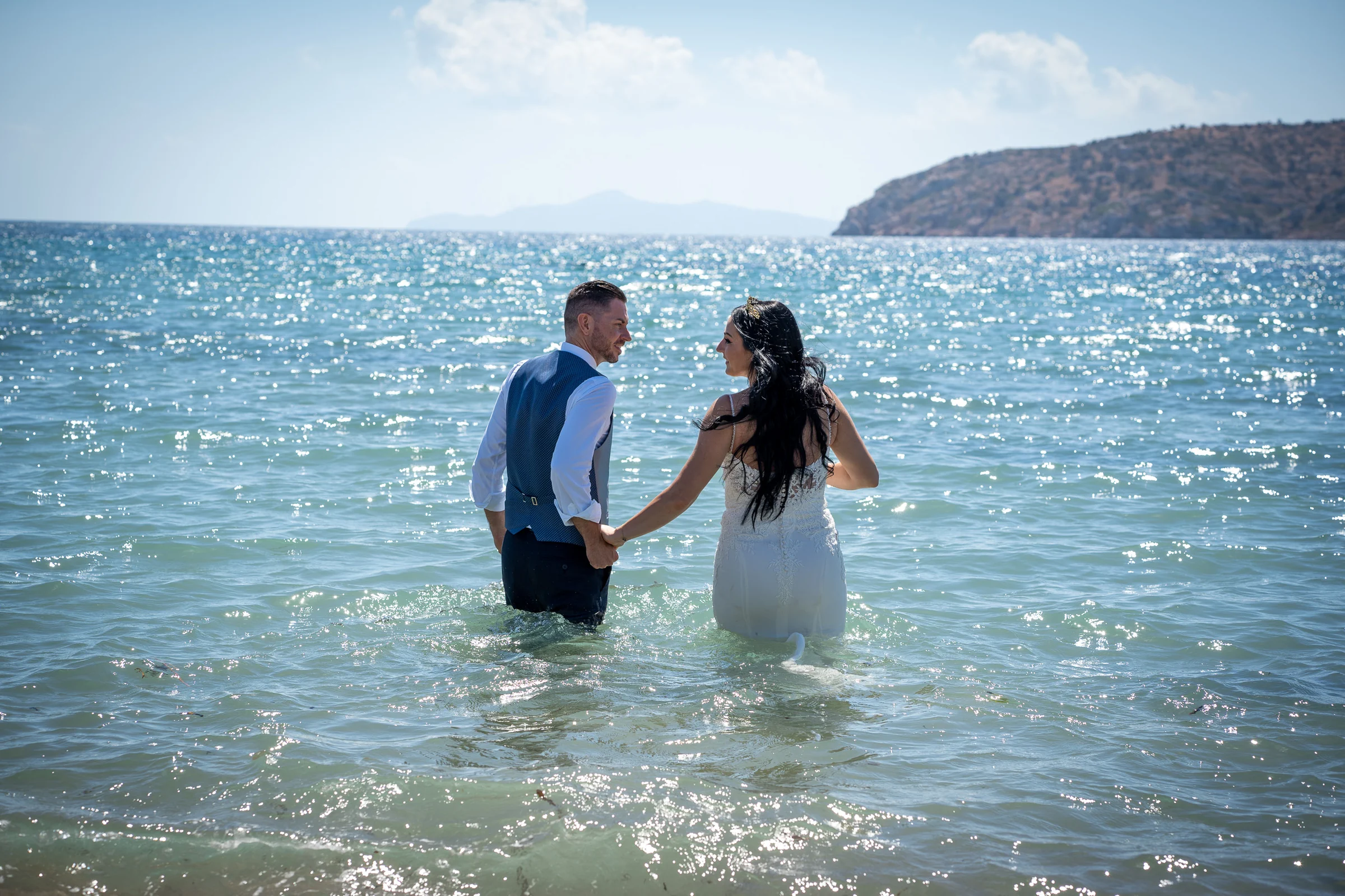 Sara y Edu avanzan de la mano dentro del mar Egeo durante la parte final de su postboda en Grecia.