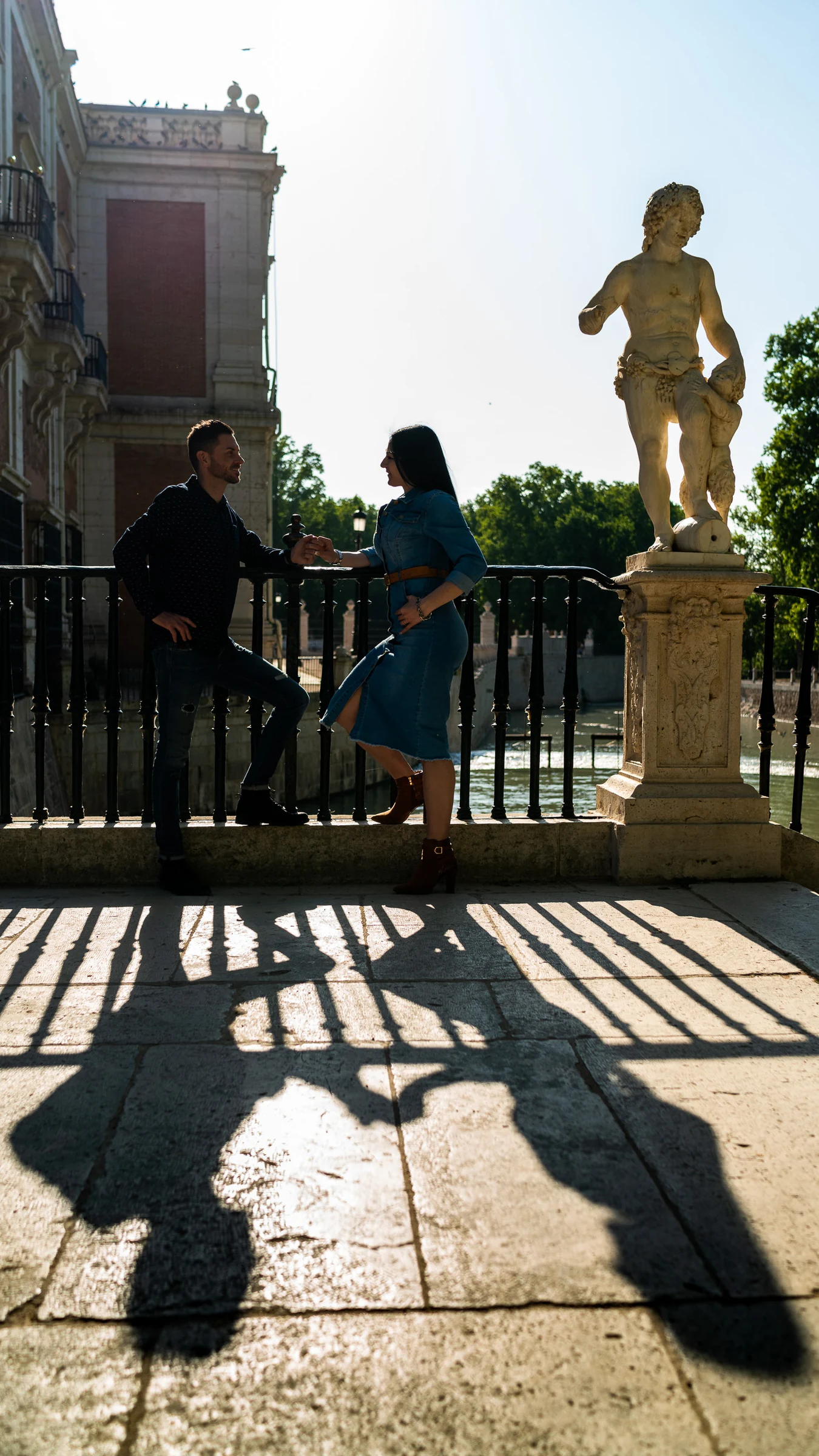 Sara y Edu pasean por los jardines de Aranjuez mientras sus sombras se proyectan sobre el suelo al final de la tarde.