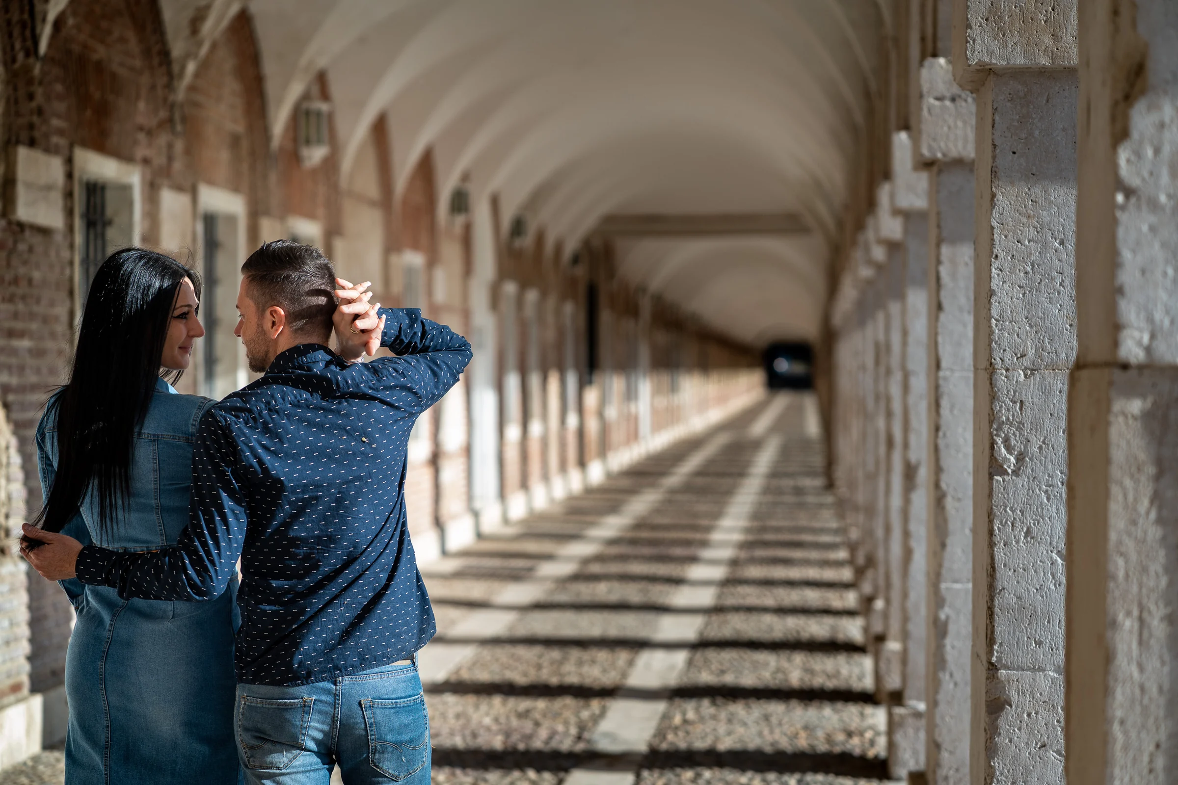 Sara y Edu se abrazan bajo los arcos de una galería histórica durante su preboda en Aranjuez.