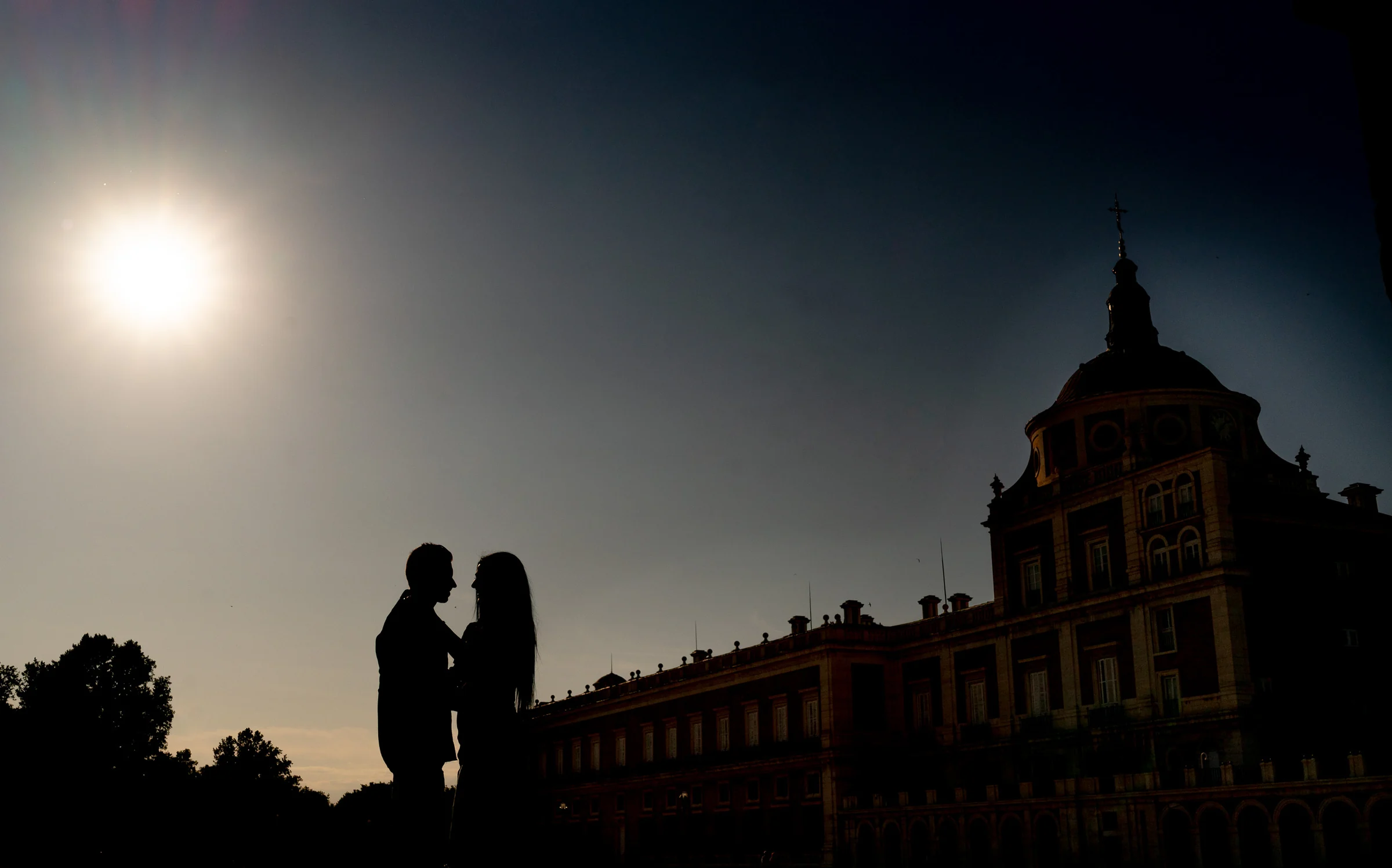 Silueta de Sara y Edu besándose al atardecer con el Palacio Real de Aranjuez al fondo durante su preboda.