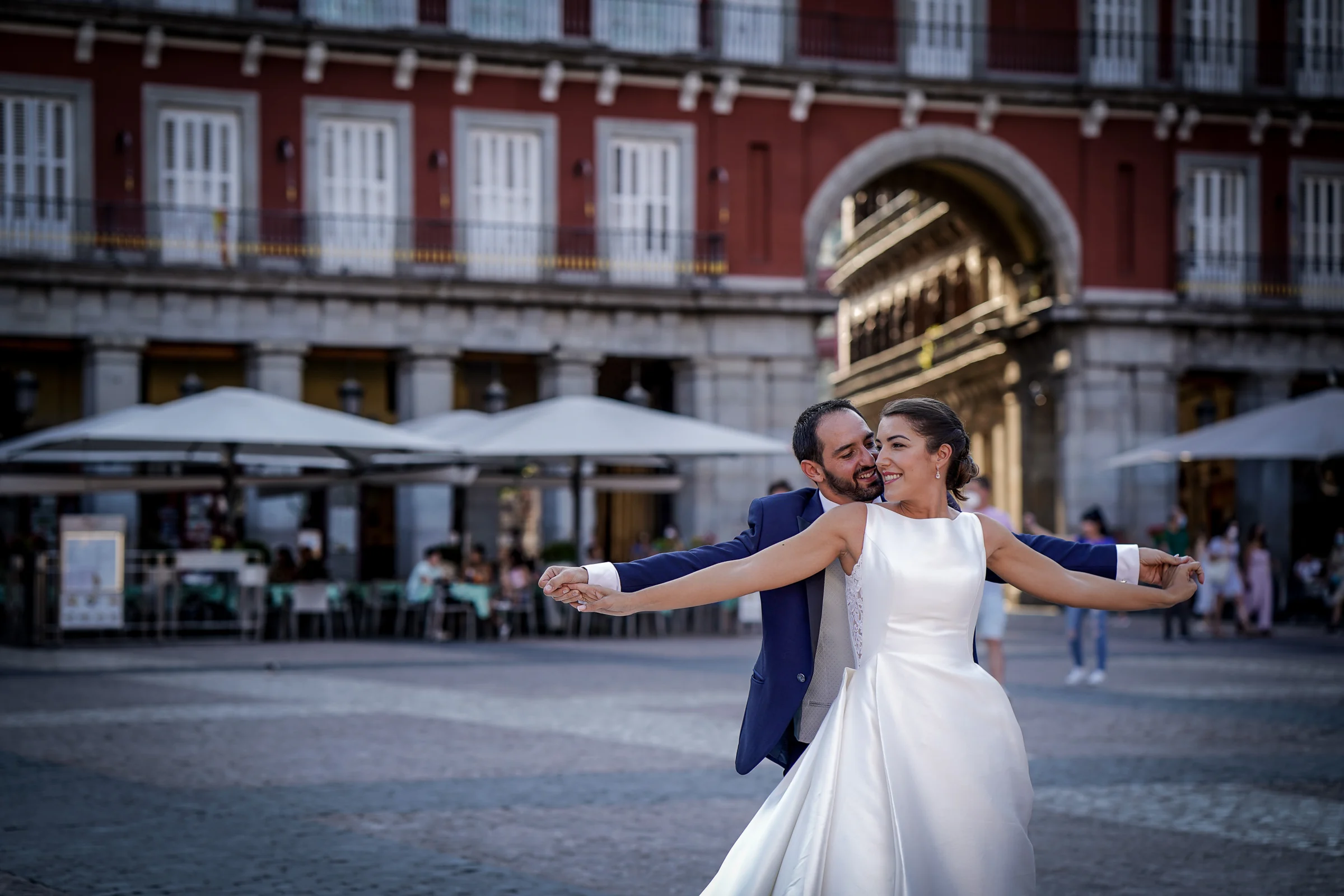 Sara y Edu juegan con los brazos abiertos en la Plaza Mayor durante su postboda por el centro de Madrid.