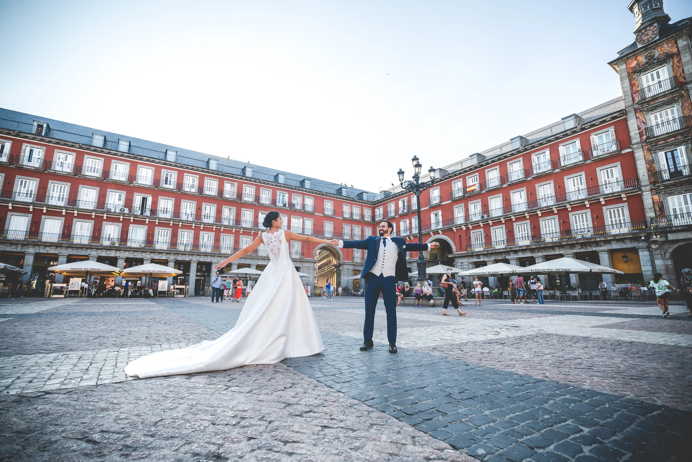 Sara y Edu se dan la mano en el centro de la Plaza Mayor, con sus fachadas rojas como escenario de su postboda en Madrid.