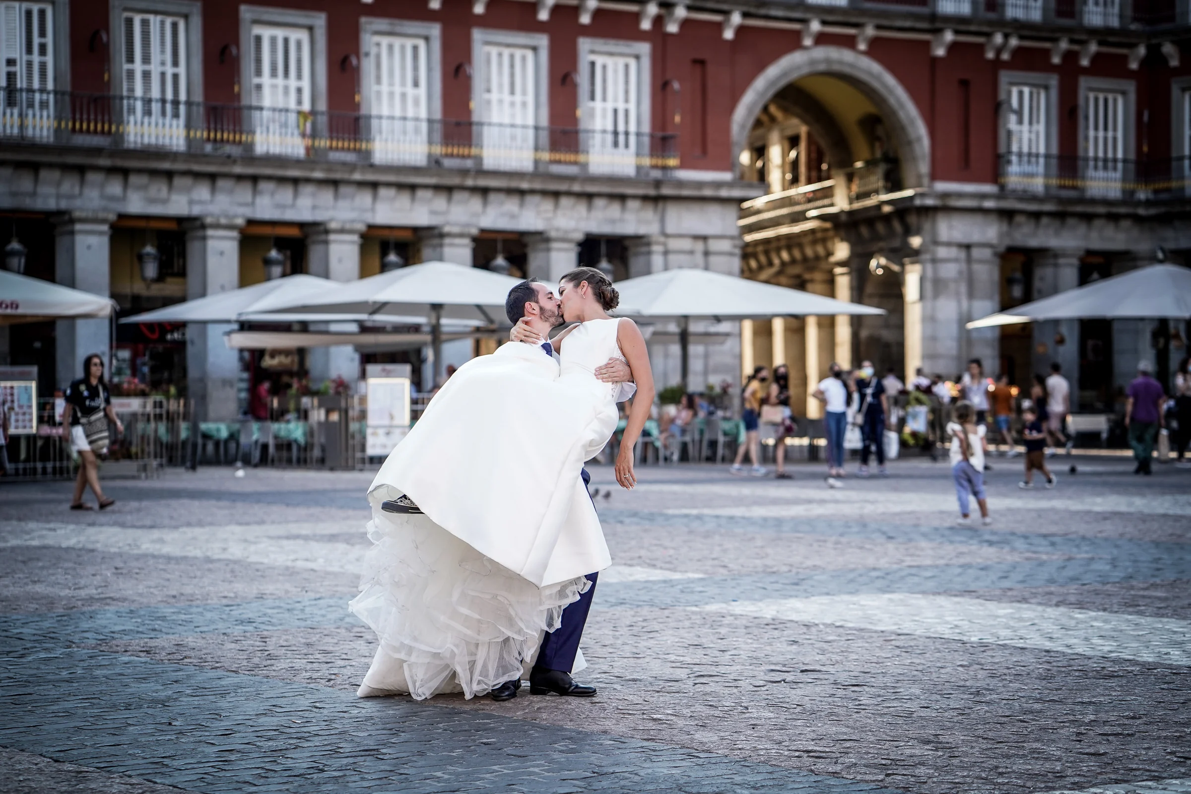 Edu sostiene a Sara mientras se besan en la Plaza Mayor durante una escena divertida de su postboda en Madrid.