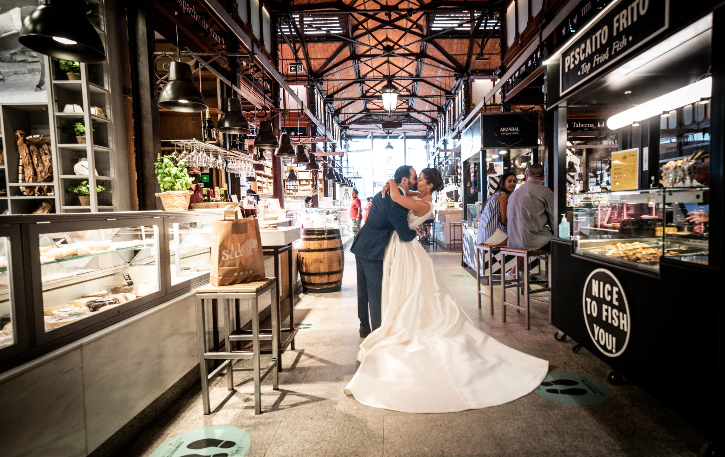 Sara y Edu se besan en uno de los pasillos del Mercado de San Miguel durante su sesión de postboda en Madrid.
