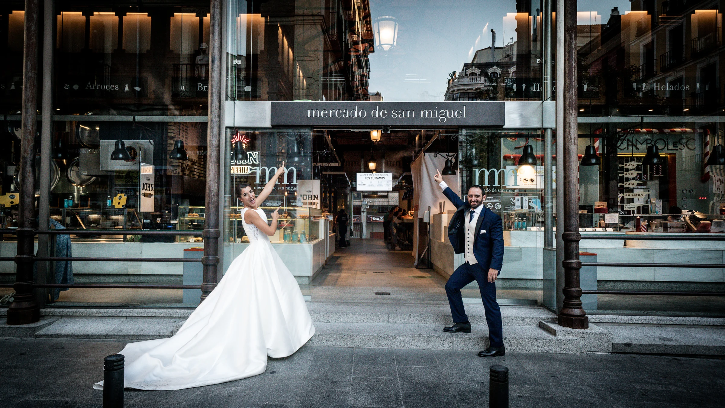 Sara y Edu posan ante la entrada del Mercado de San Miguel durante su recorrido de postboda por el centro histórico de Madrid.