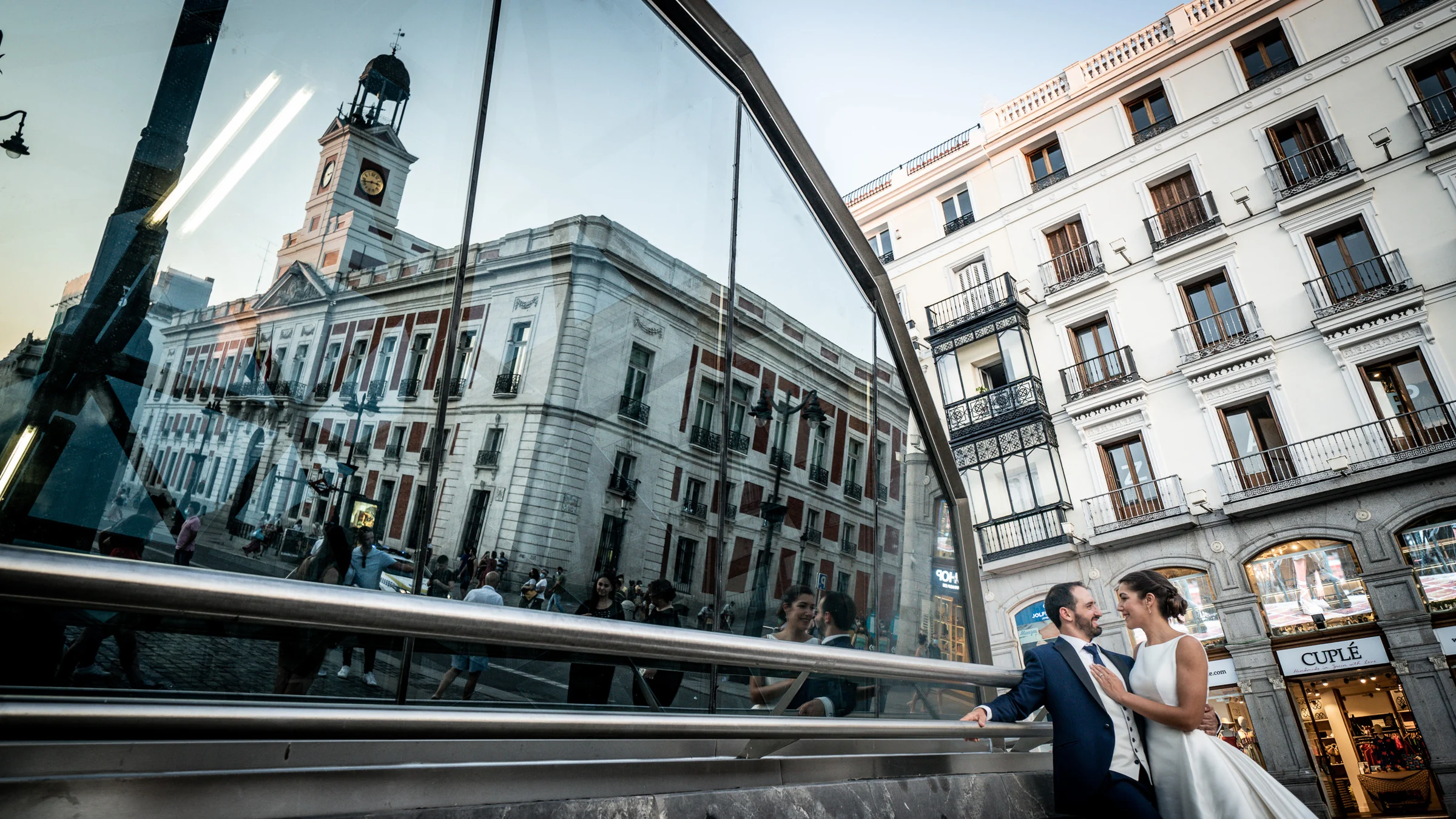 Sara y Edu aparecen junto al reflejo de la Real Casa de Correos en la Puerta del Sol durante su postboda por Madrid.