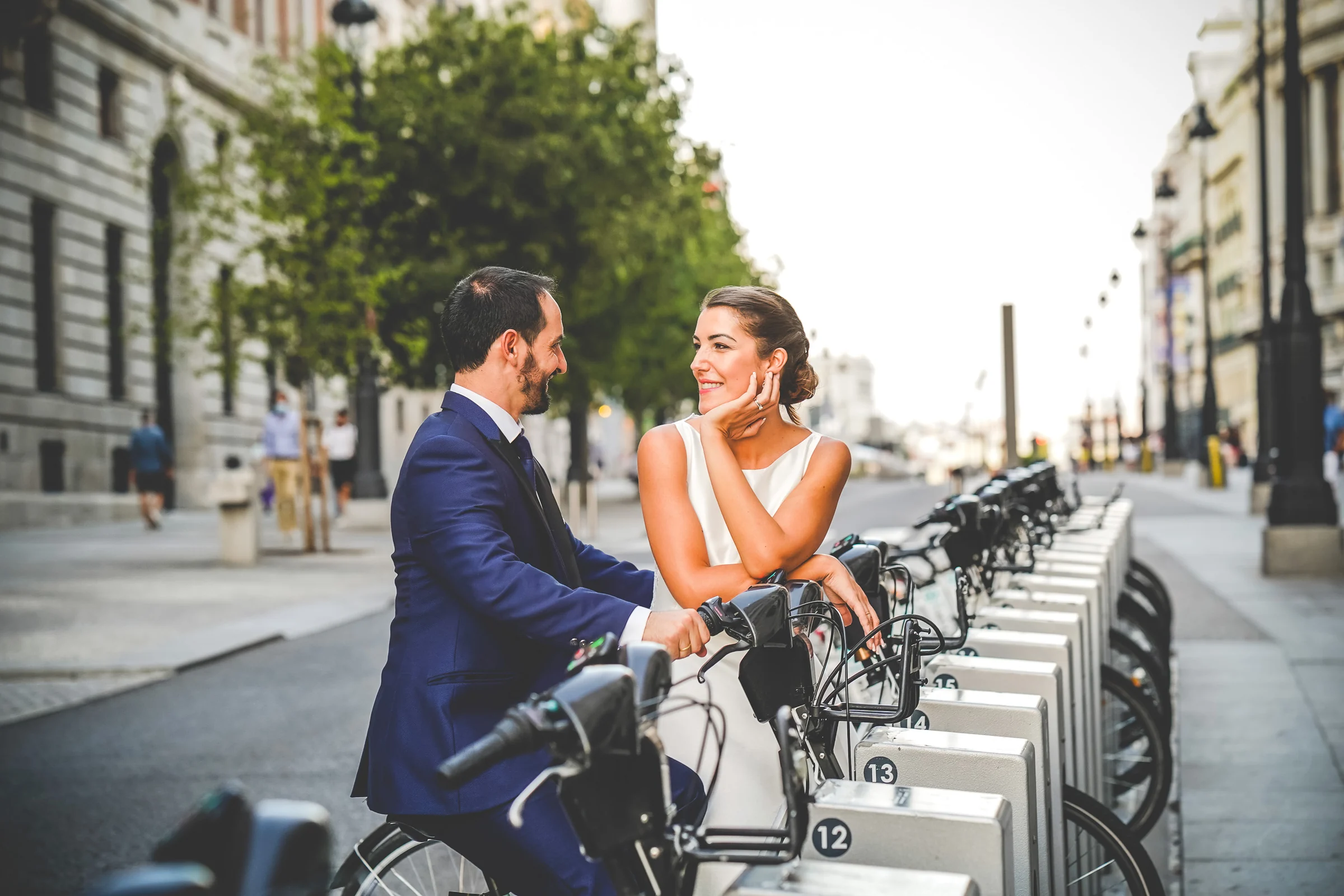 Sara y Edu conversan junto a una estación de bicicletas del centro de Madrid durante su sesión de postboda urbana.