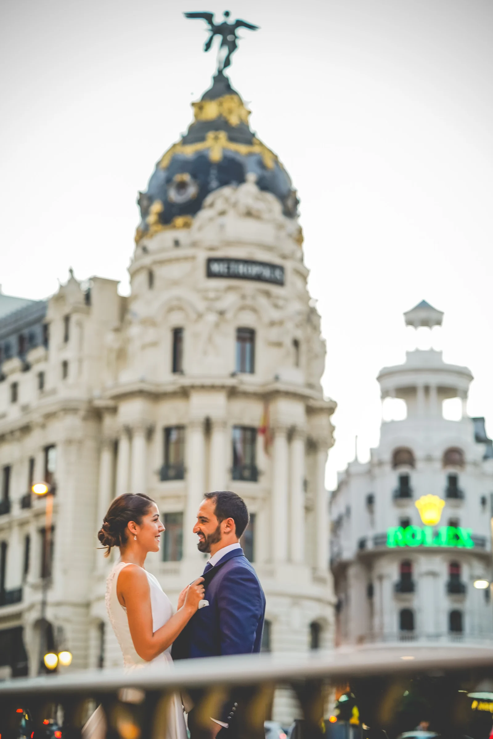 Sara y Edu se miran con el Edificio Metrópolis y la Gran Vía al fondo durante su postboda en Madrid.