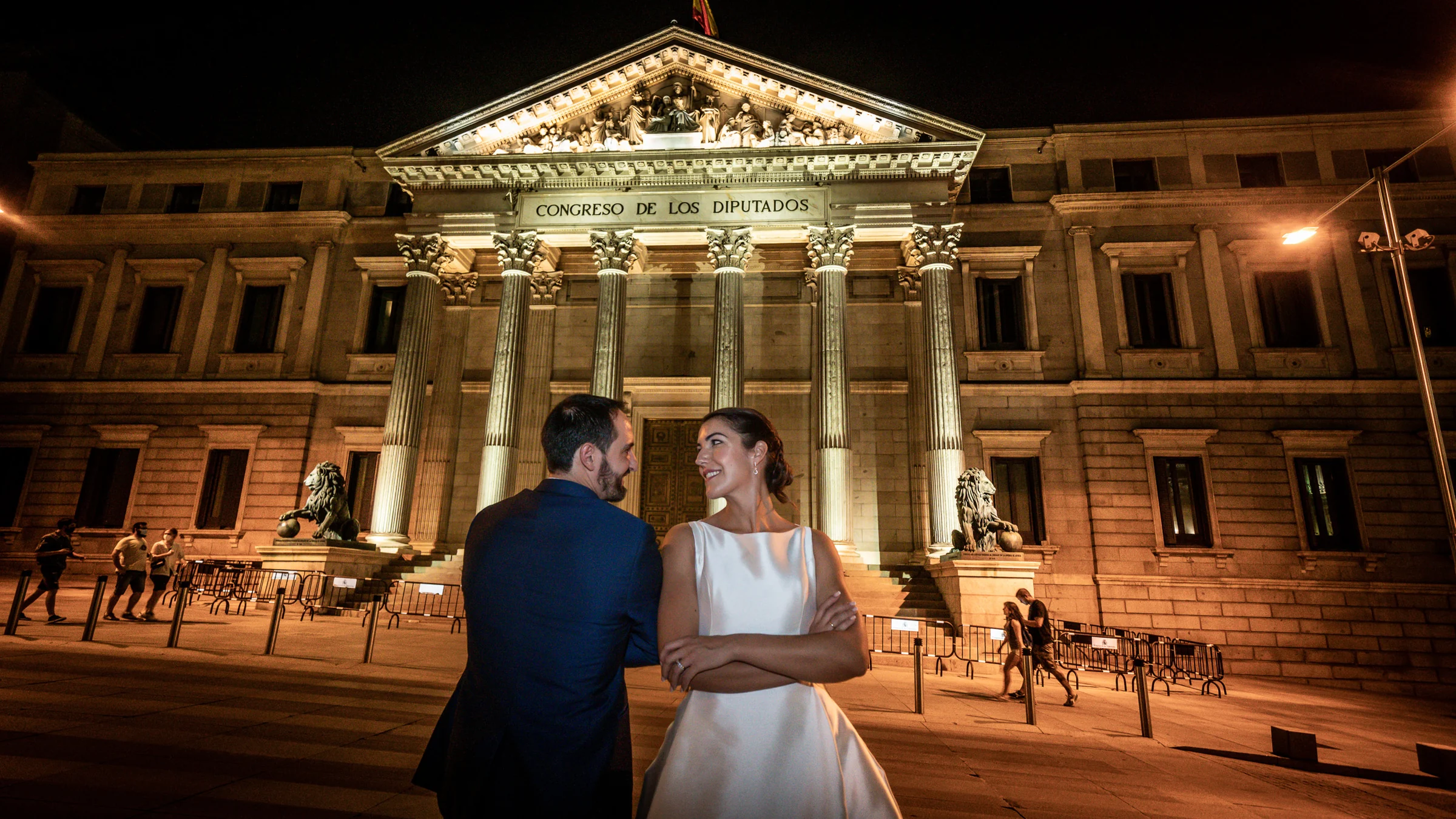 Sara y Edu posan frente al Congreso de los Diputados iluminado durante su recorrido nocturno de postboda por Madrid.