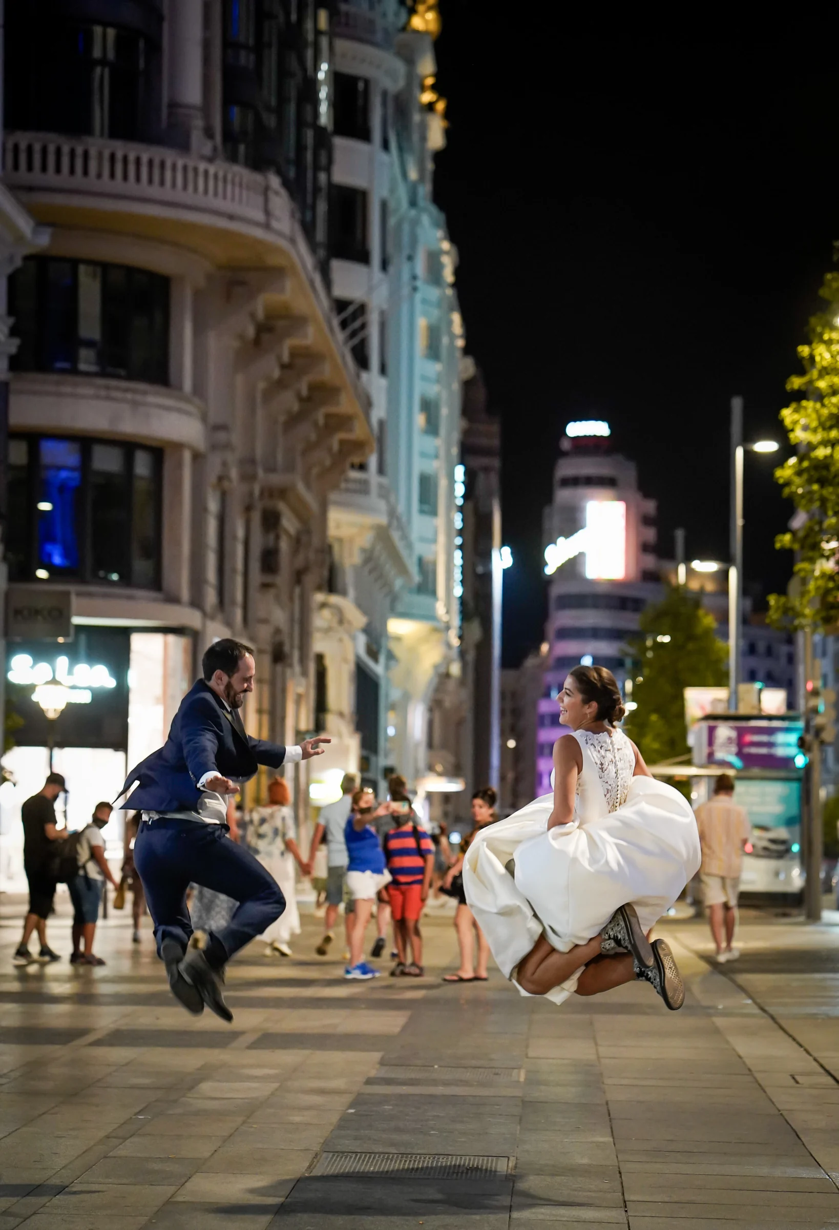 Sara y Edu saltan en una calle de Gran Vía durante la parte nocturna de su postboda en Madrid.