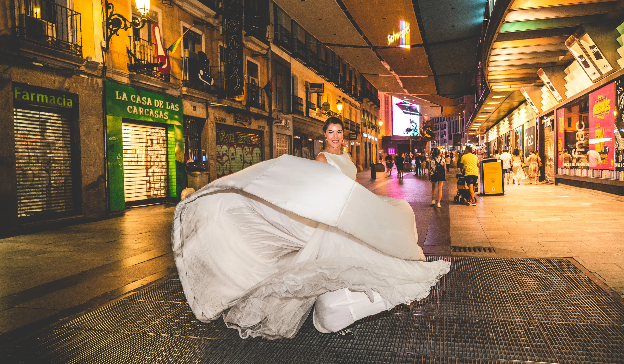 Sara hace girar su vestido en una calle peatonal de Callao durante la parte nocturna de su postboda por Madrid.