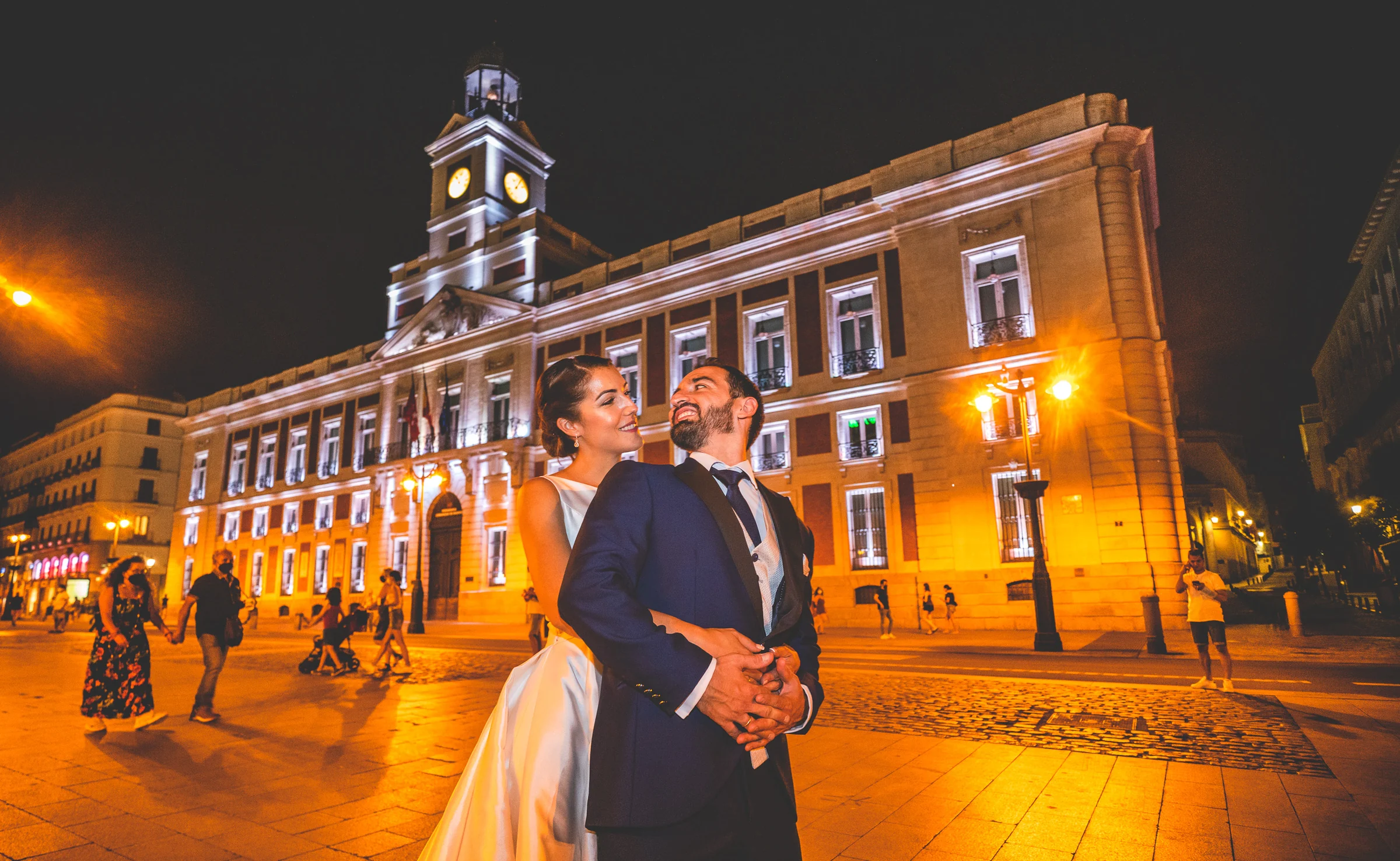 Sara abraza a Edu frente a la Real Casa de Correos iluminada en la Puerta del Sol durante el final de su postboda en Madrid.