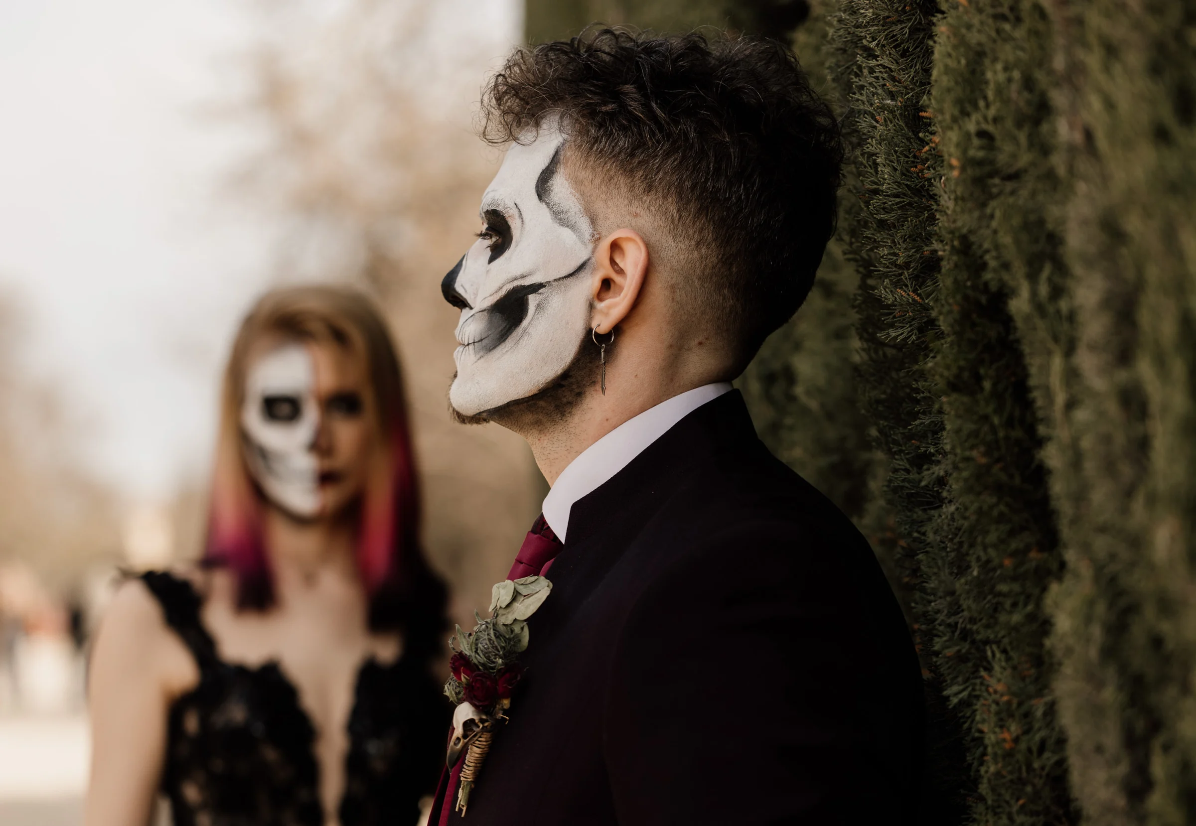 Rubén aparece en primer plano con maquillaje de calavera mientras Silvia queda desenfocada al fondo en El Retiro.