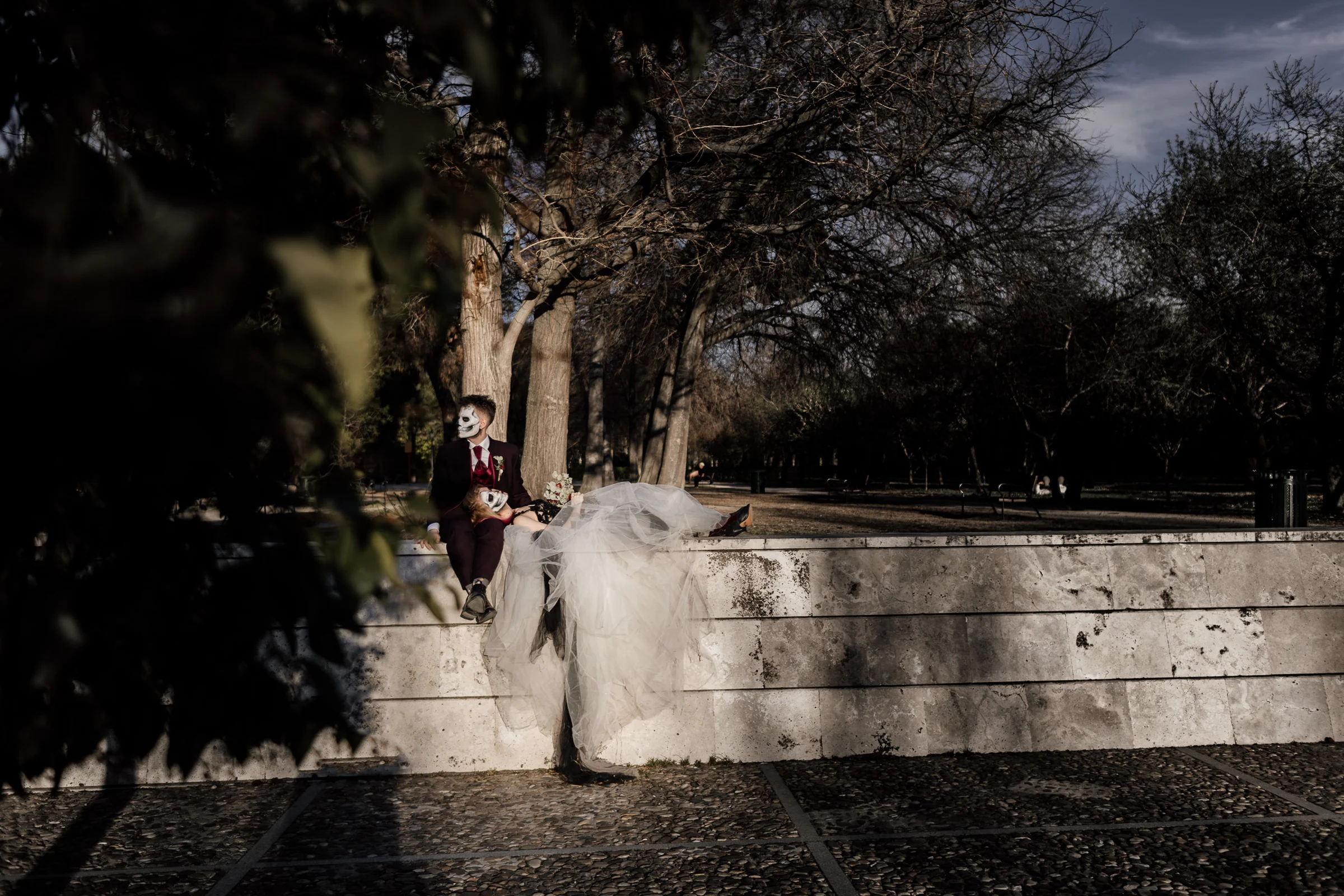 Silvia se recuesta sobre Rubén en un muro de piedra entre los árboles de El Retiro durante la parte final de su postboda gótica.