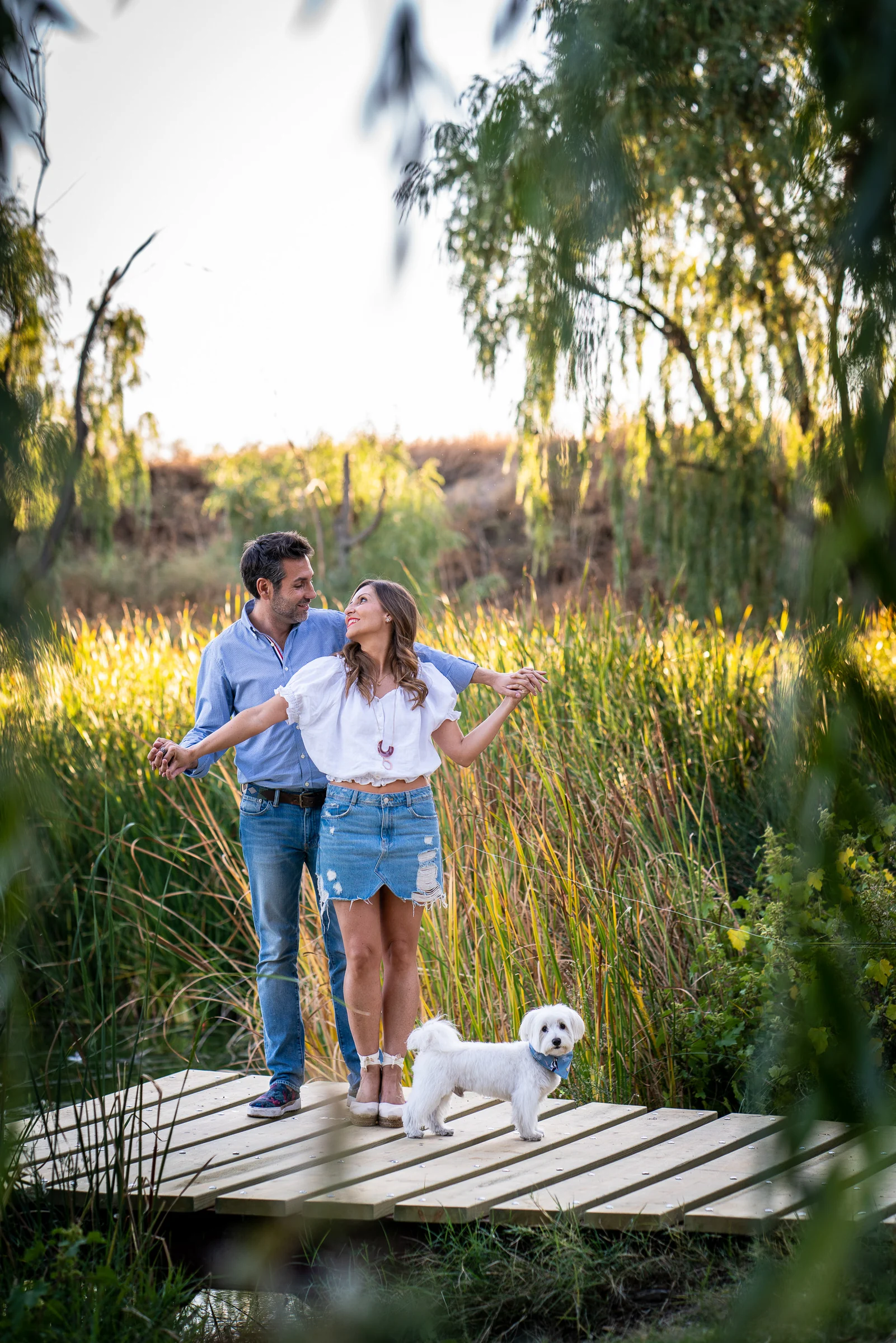 Vanesa y Fran avanzan entre vegetación alta y luz dorada durante su preboda en un parque de Madrid.