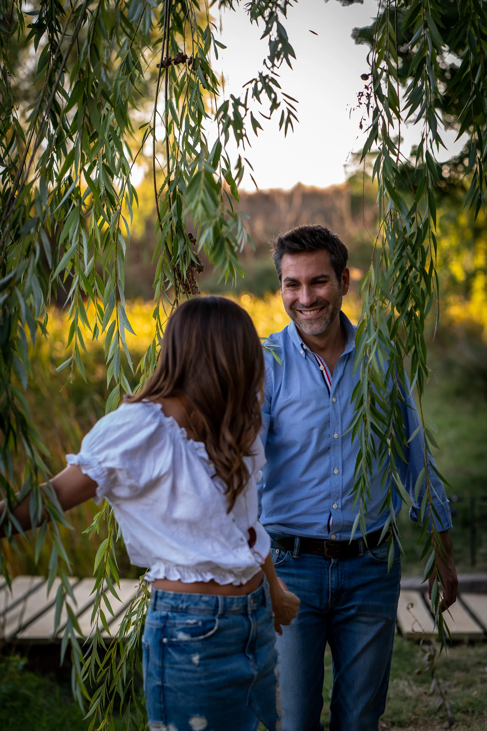 Vanesa sonríe a Fran entre las ramas de los árboles durante su sesión de preboda en Madrid.