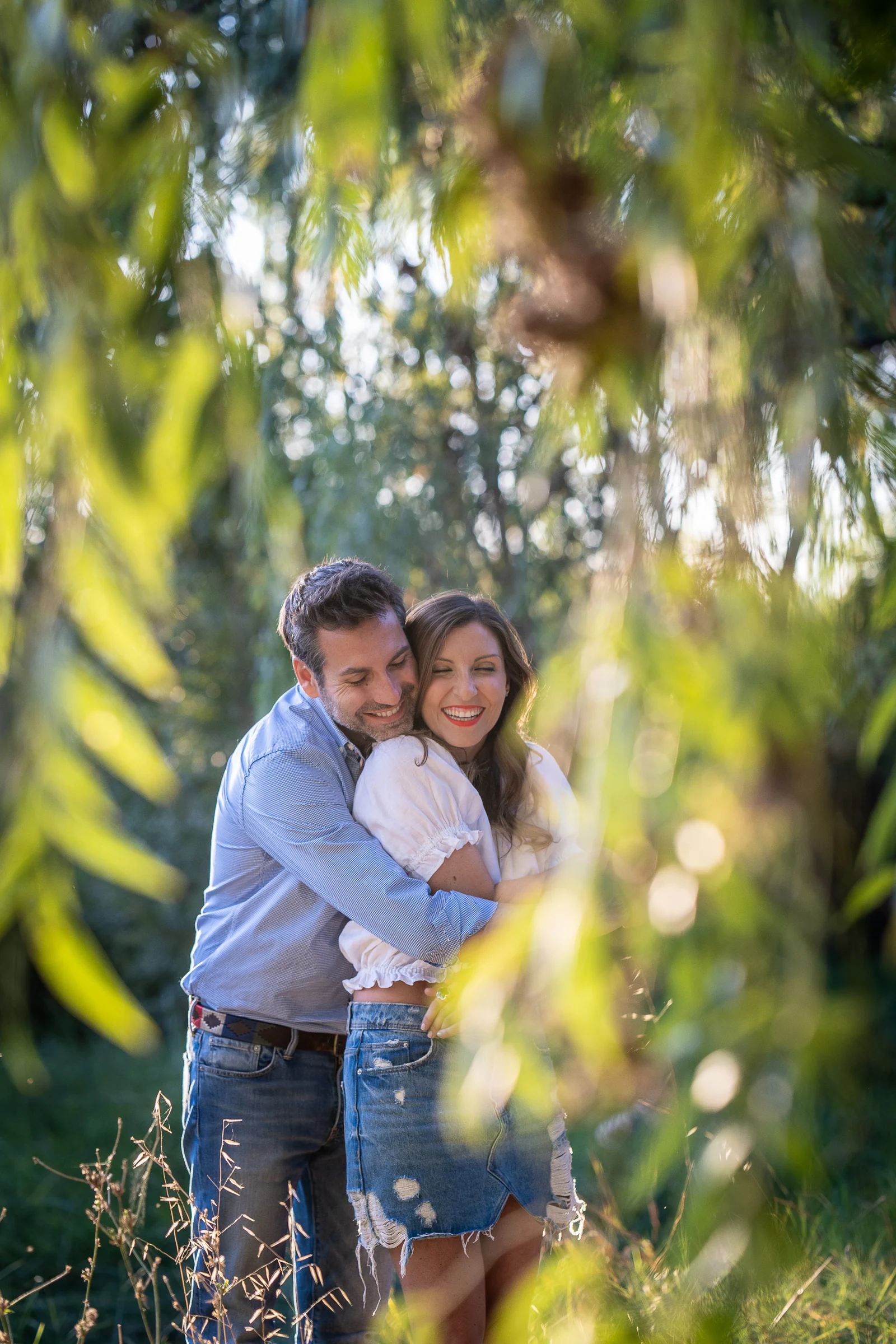 Vanesa y Fran se abrazan entre hojas desenfocadas durante su preboda en un parque de Madrid.